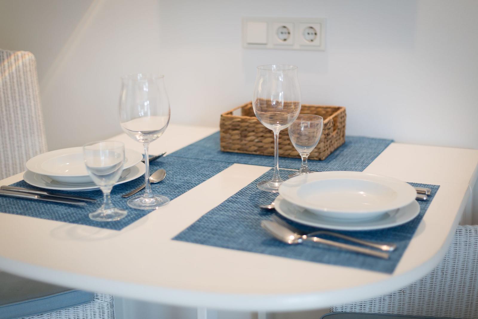 Tisch mit Platzierung für zwei Personen, blauen Tischdecken und Gläsern.