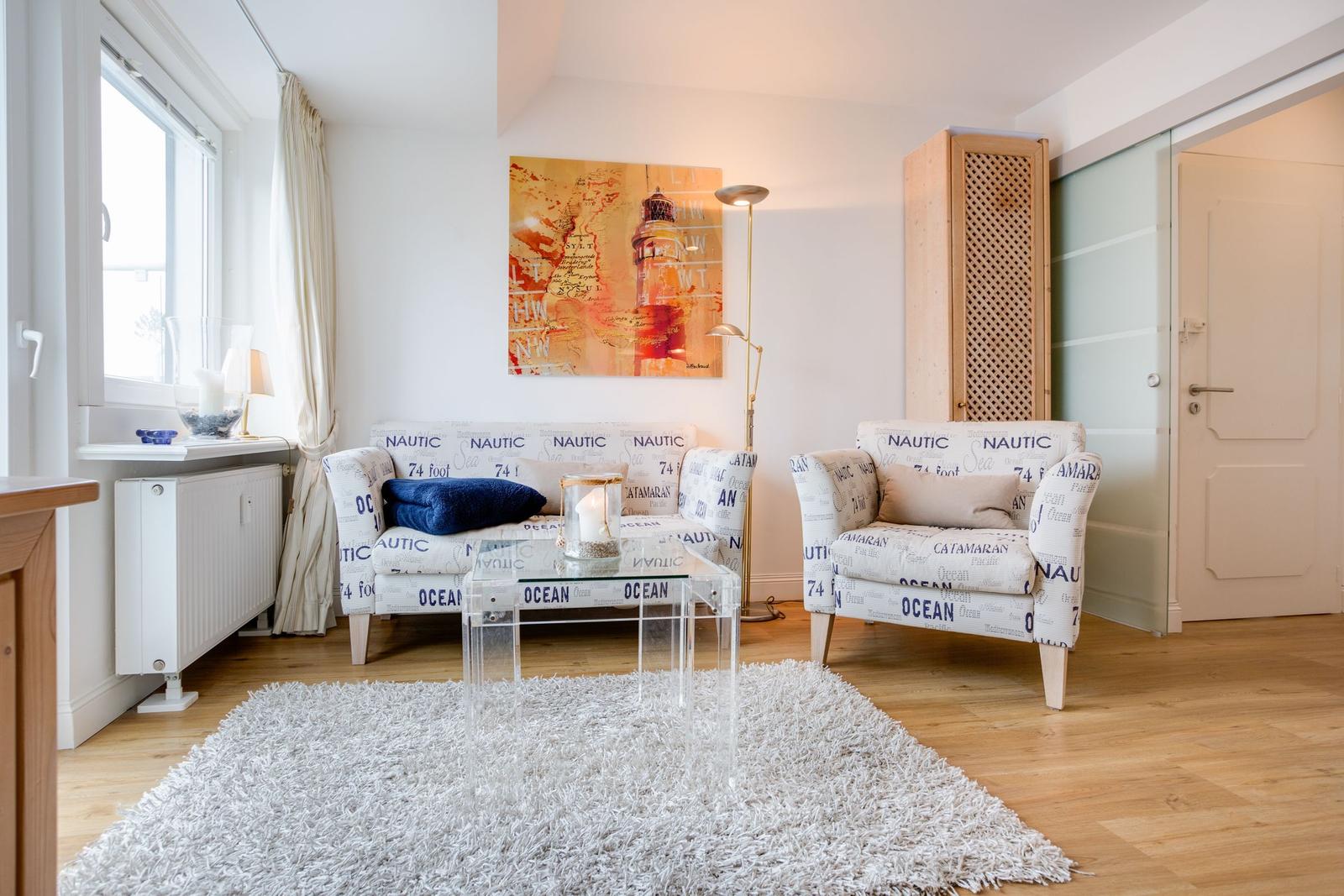 Wohnzimmer mit Sofa, Sessel und Glas-Tisch auf Teppich