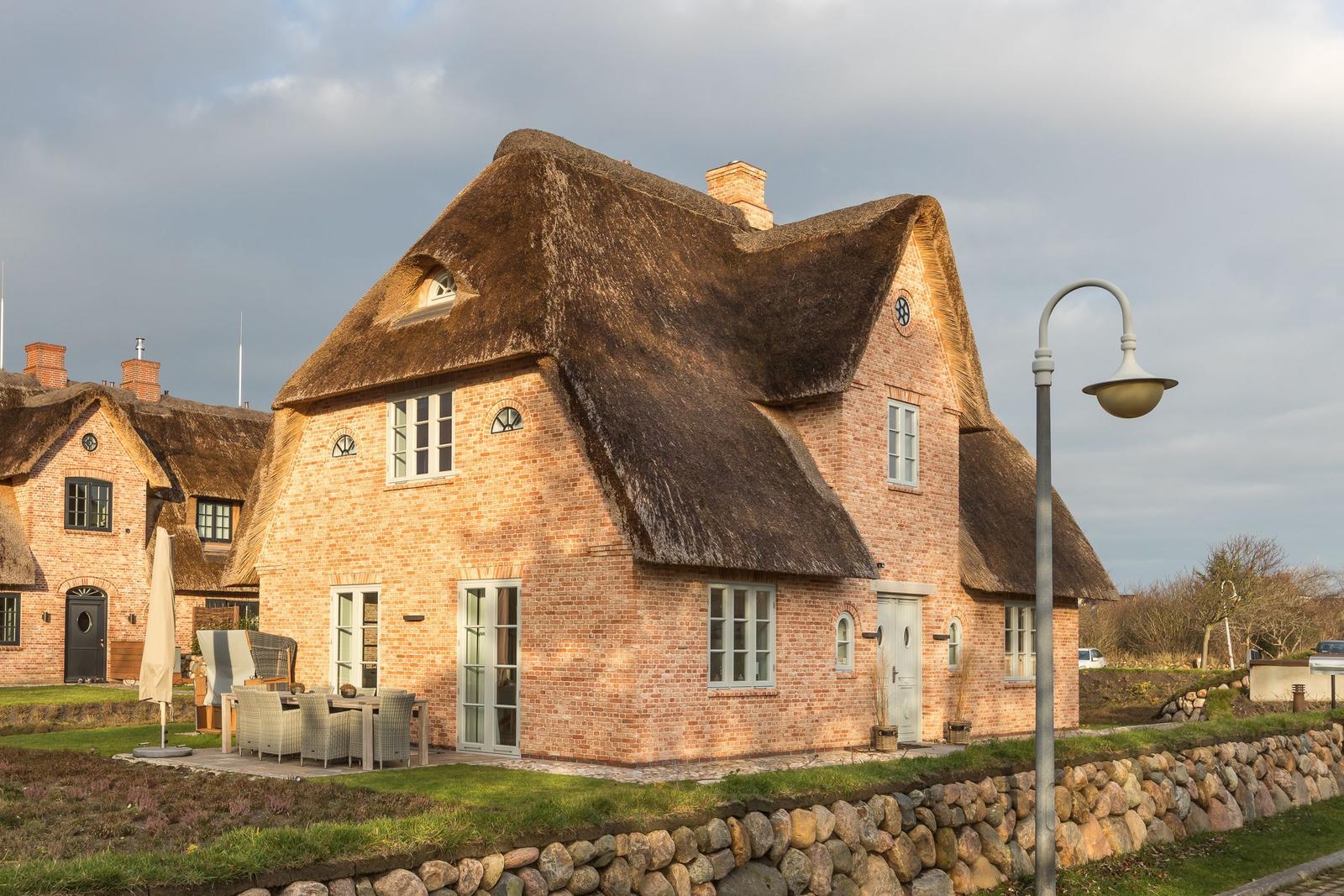 Haus mit Strohdach, Terrasse und Steinmauer