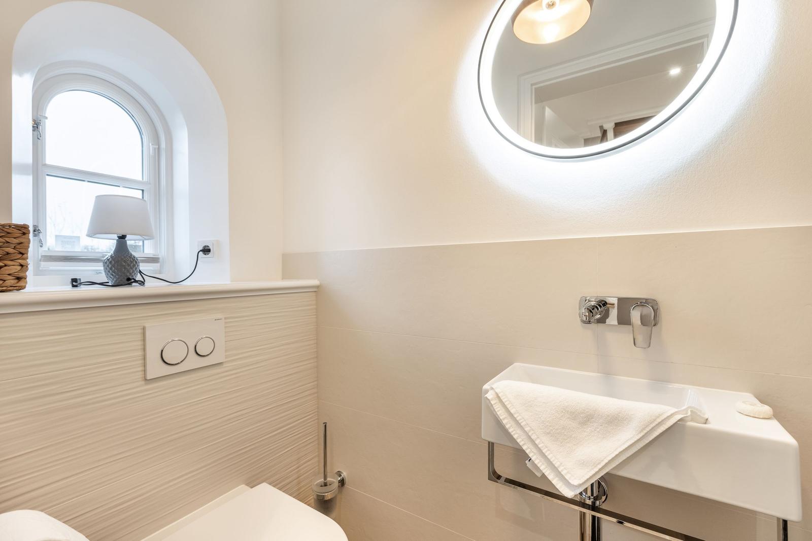 Badezimmer mit Waschbecken, Spiegel und Fenster