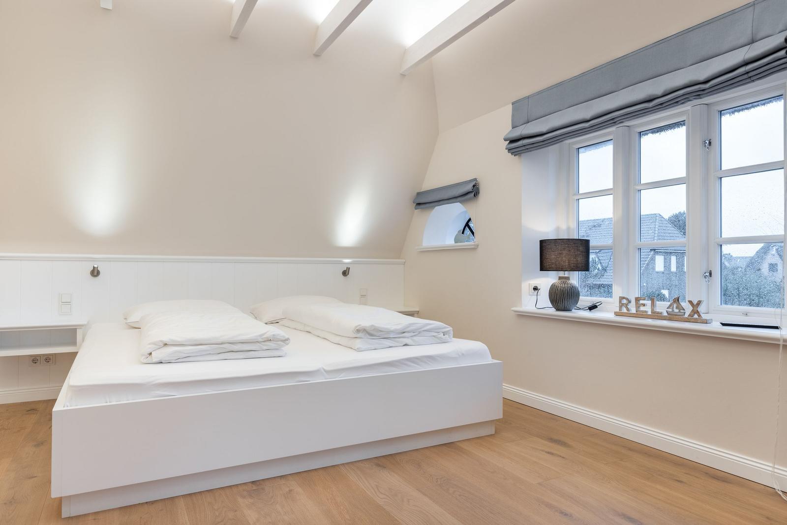 Schlafzimmer mit Doppelbett, Holzboden und Fenster mit Blick.