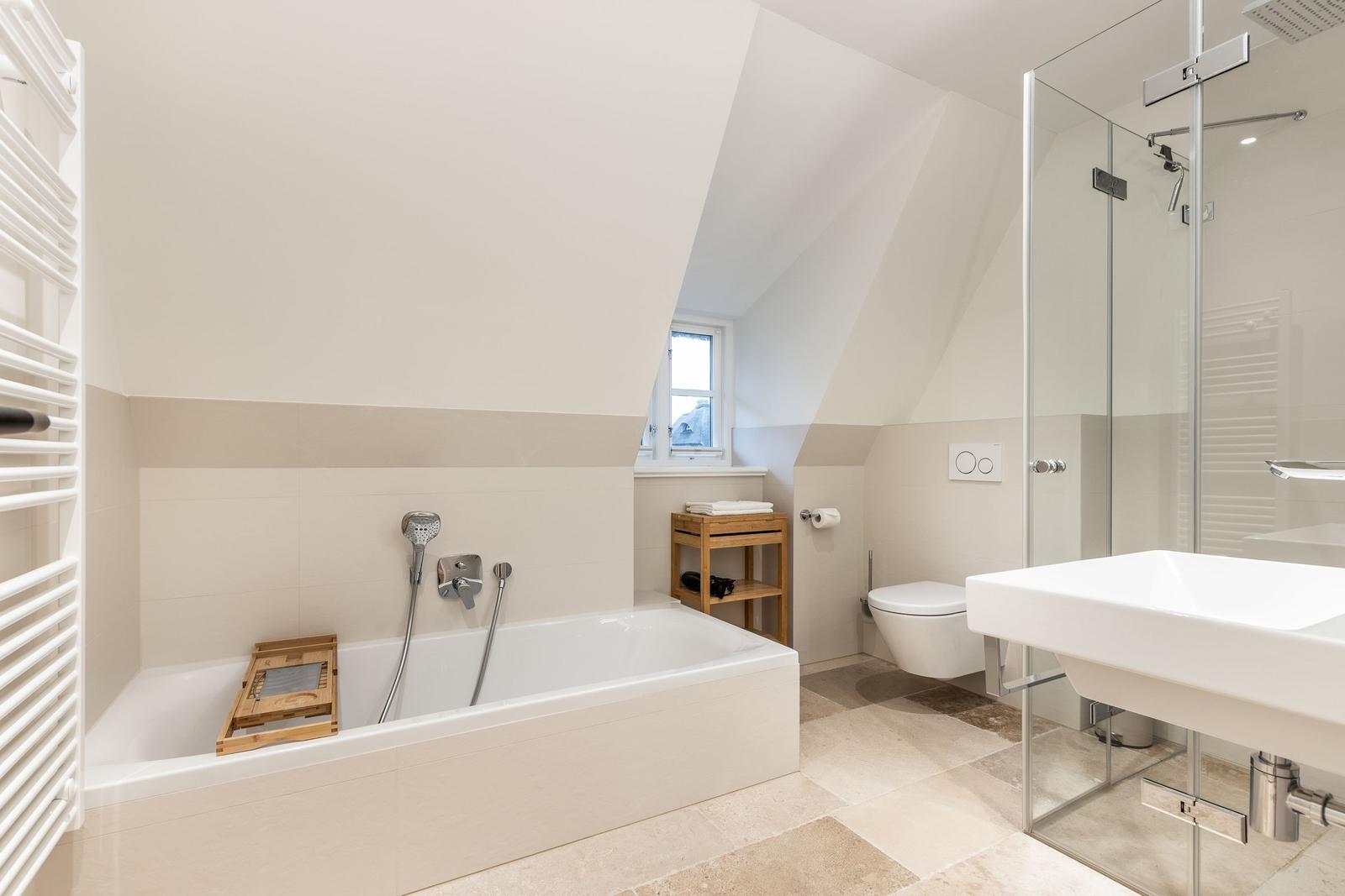 Bad mit Badewanne, Dusche und Toilette unter Dachschrägen.