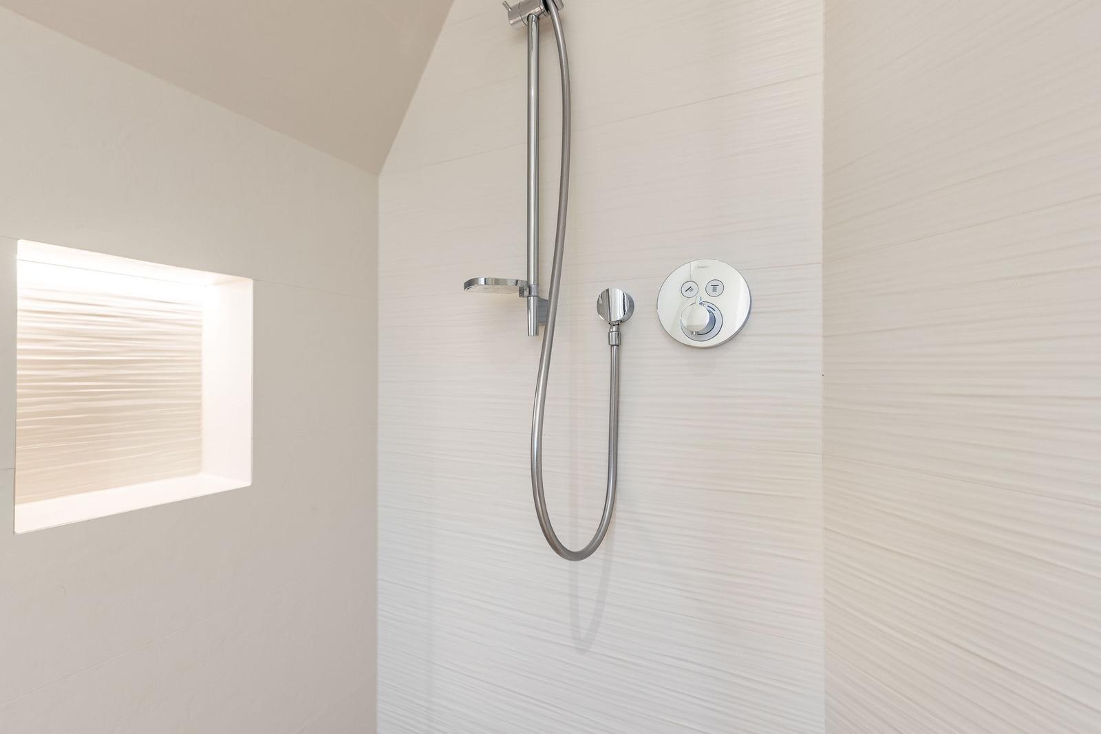 Dusche mit Duschbrause und Duschwand. Fenster mit Jalousie.