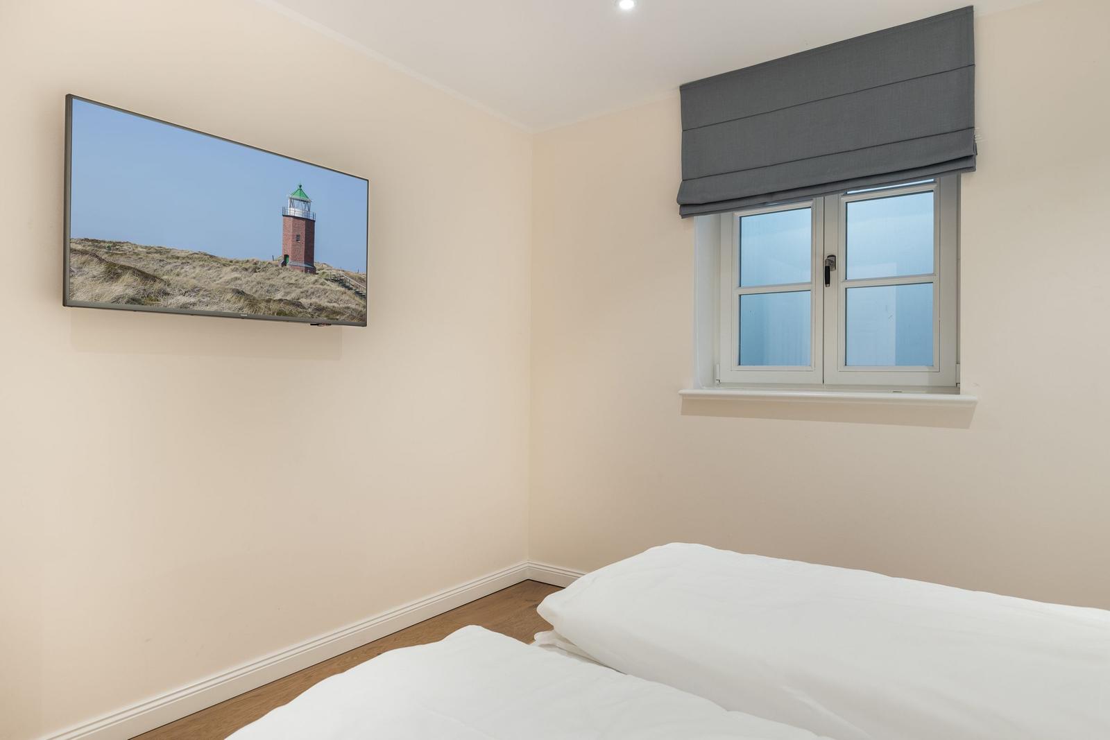 Schlafzimmer mit Bett, Fenster und Wandbild eines Leuchtturms.