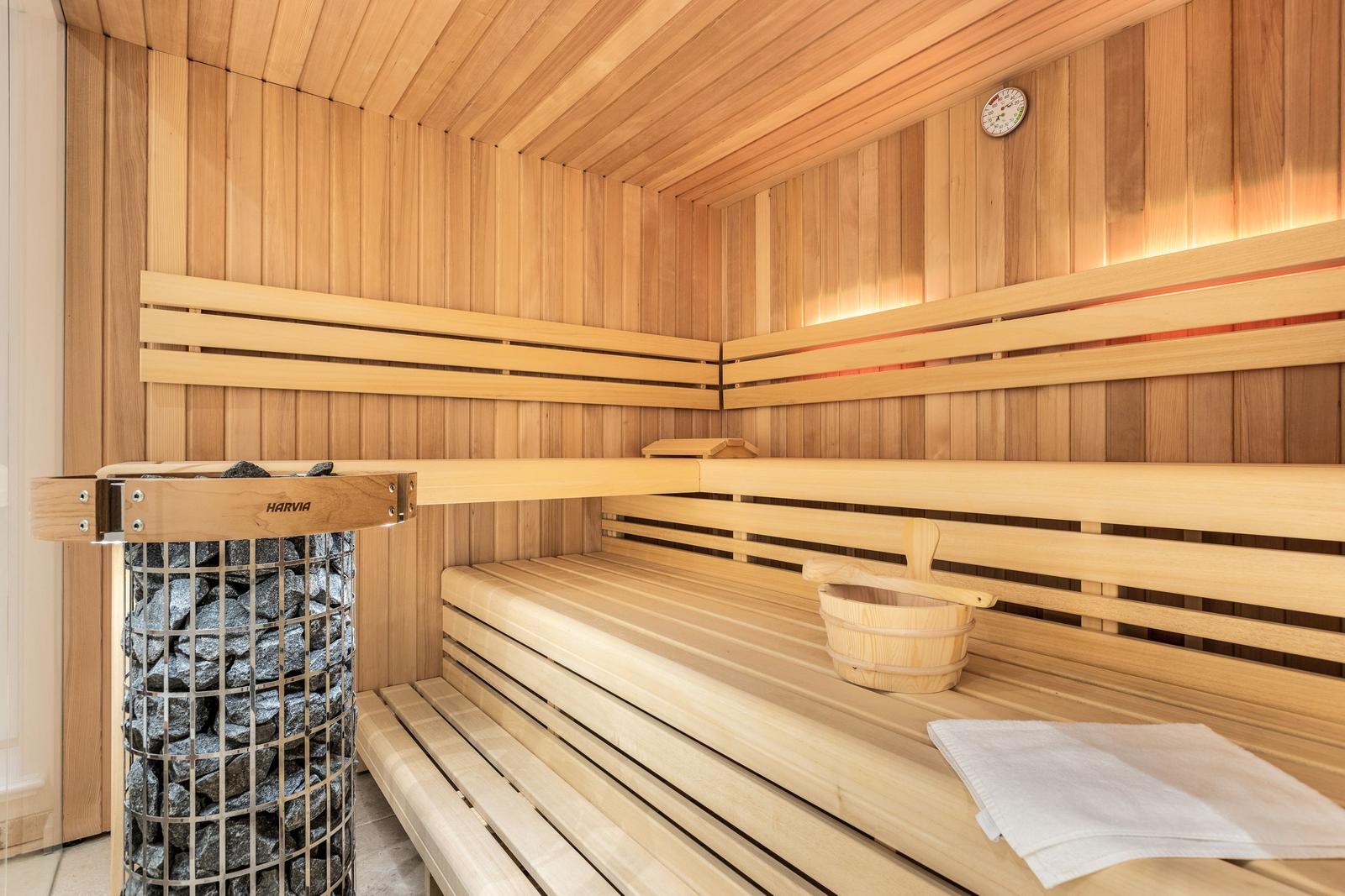 Sauna mit Holzbänken, Steinkessel und Holzschale.