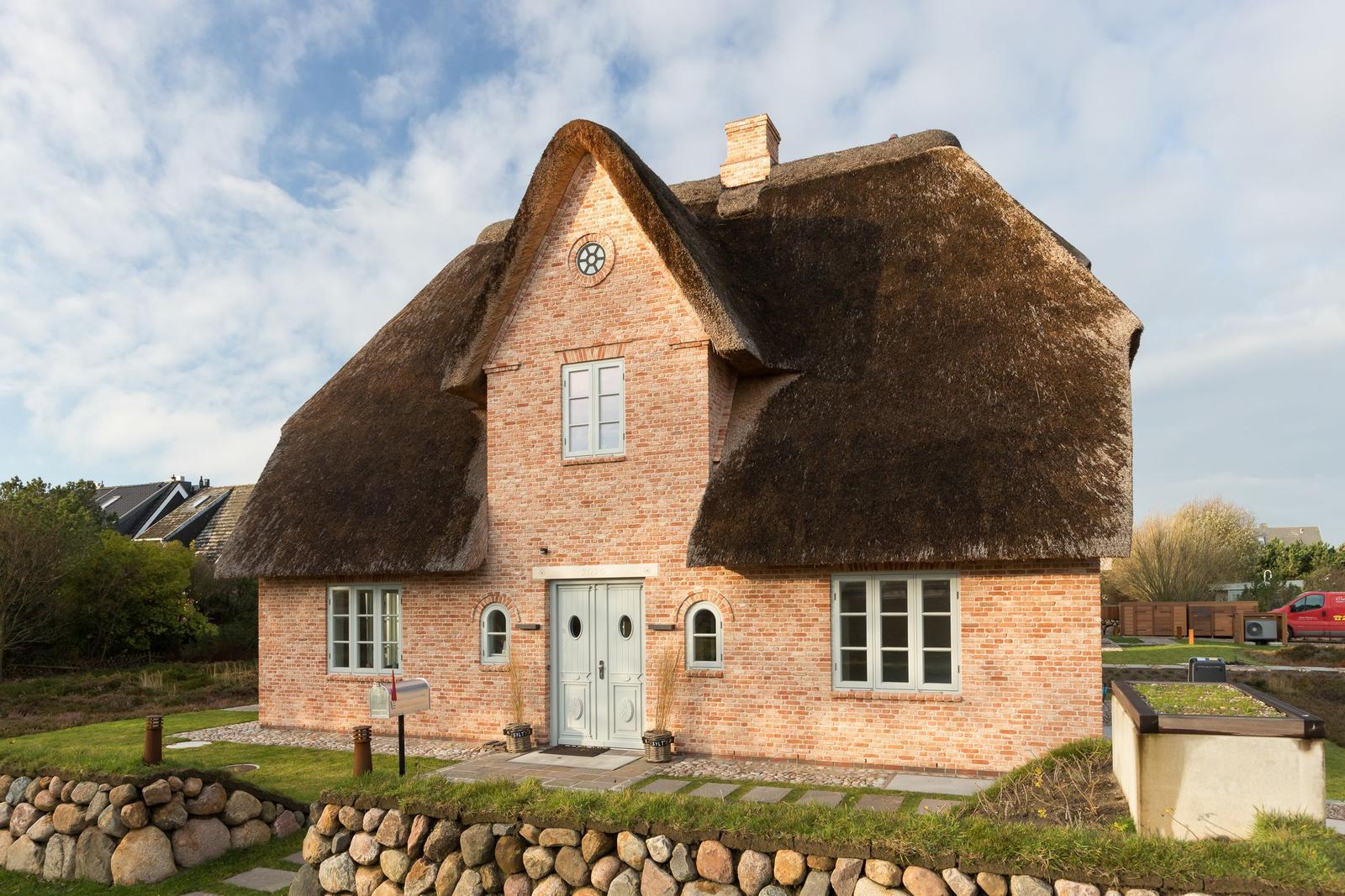 Haus mit strohgedecktem Dach und Backsteinfassade