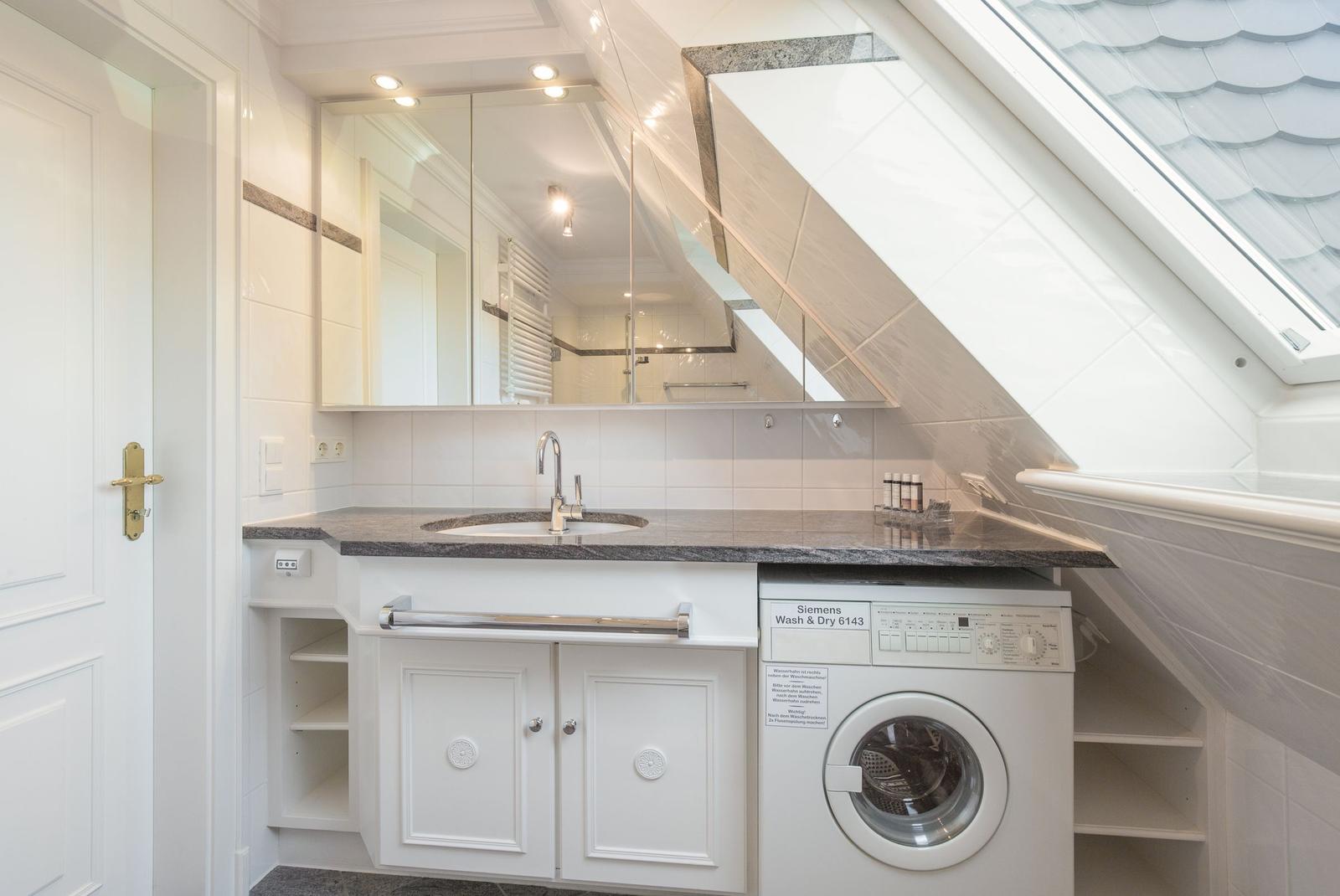 Washroom with washing machine and mirror cabinet under sloped roof.