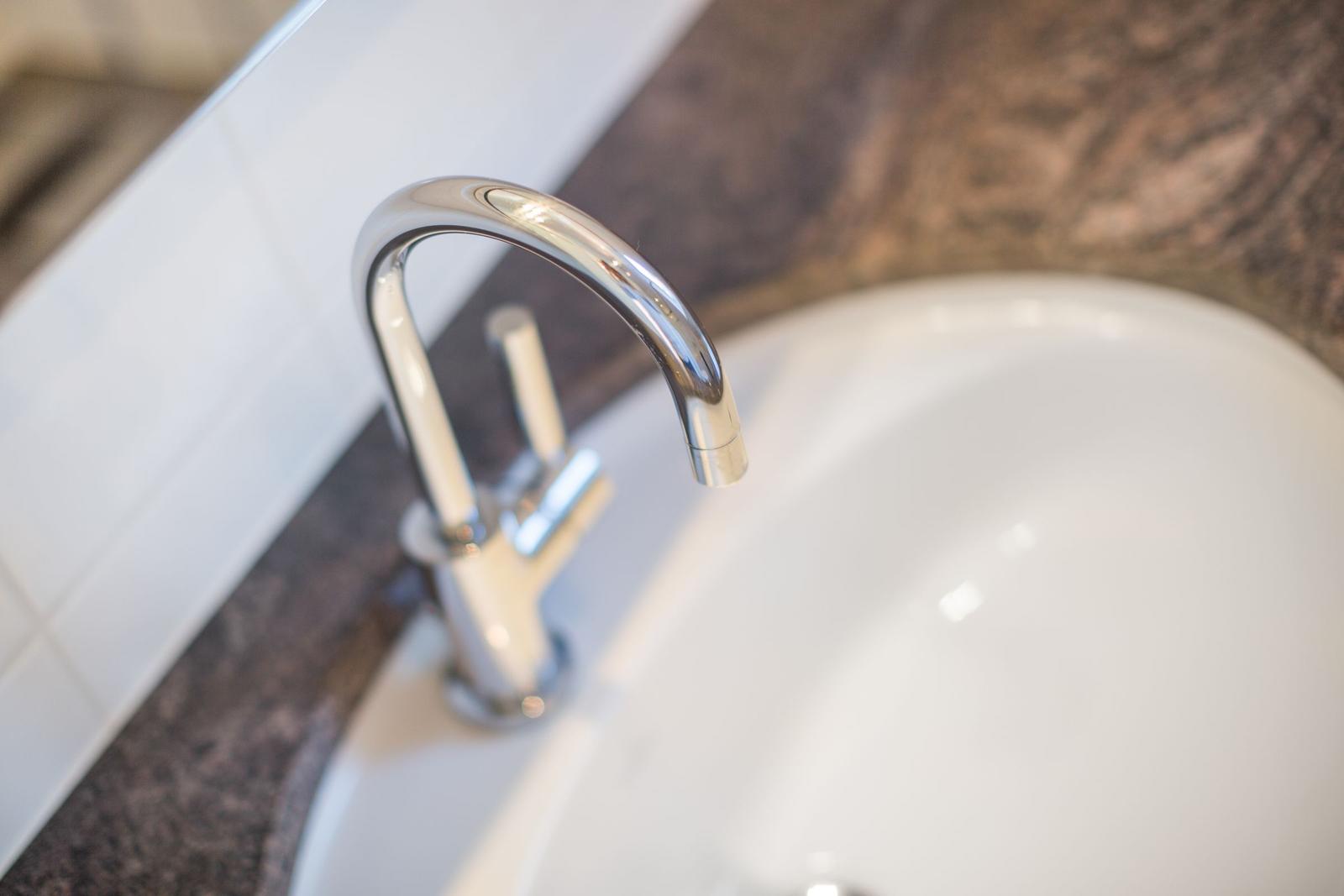 Modern sink with chrome faucet on dark marble countertop.