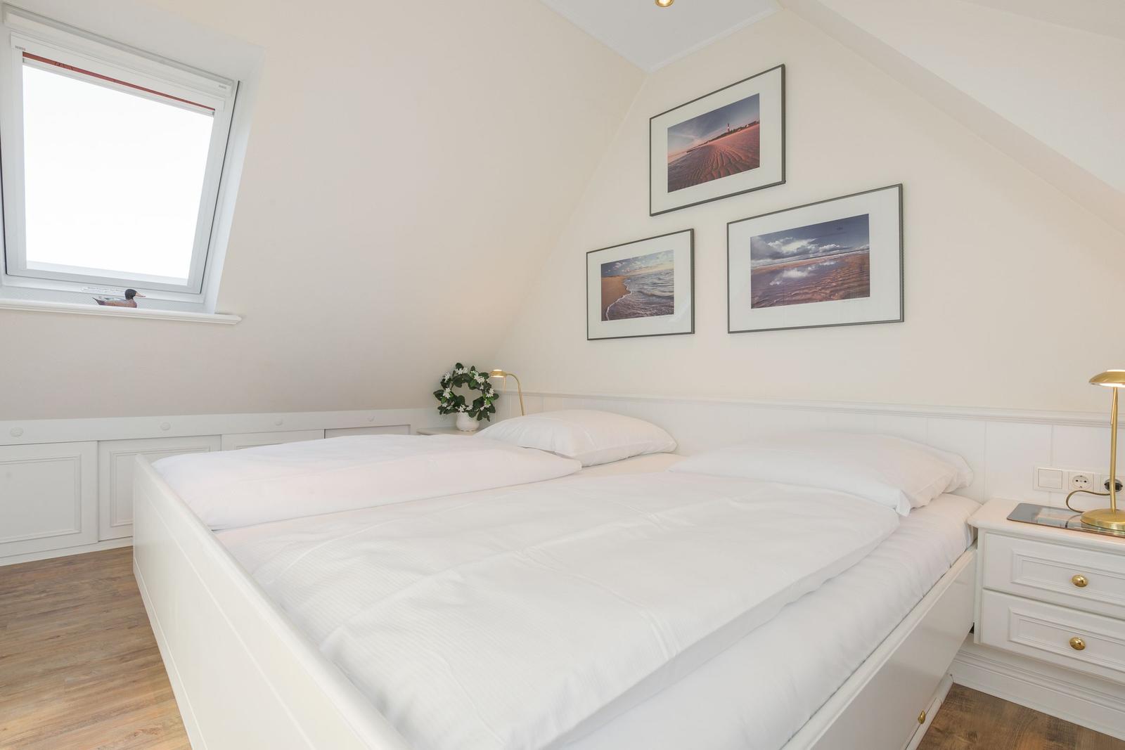 Bedroom with double bed, window, and wall pictures.