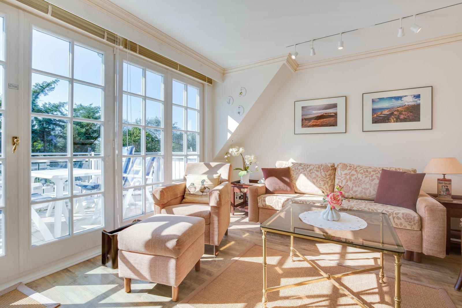 Living room with seating group, glass table, and large window to terrace.