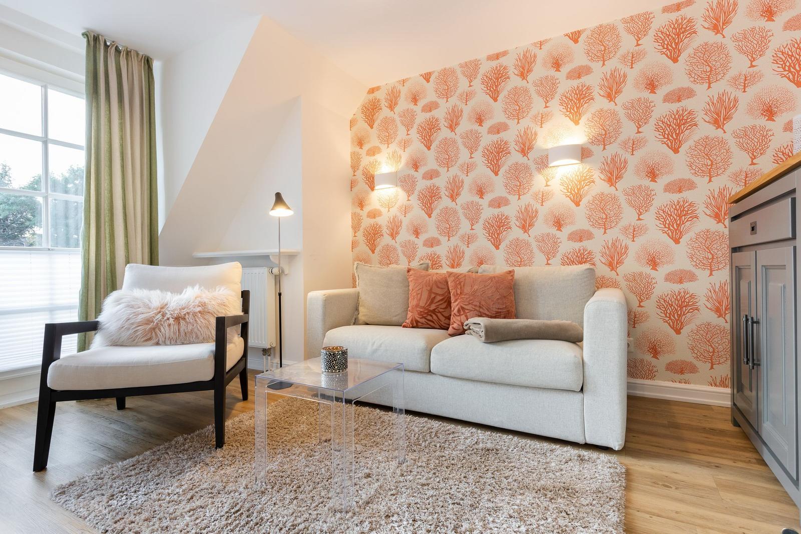 Living room with sofa, armchair, and orange patterned wallpaper on the wall.