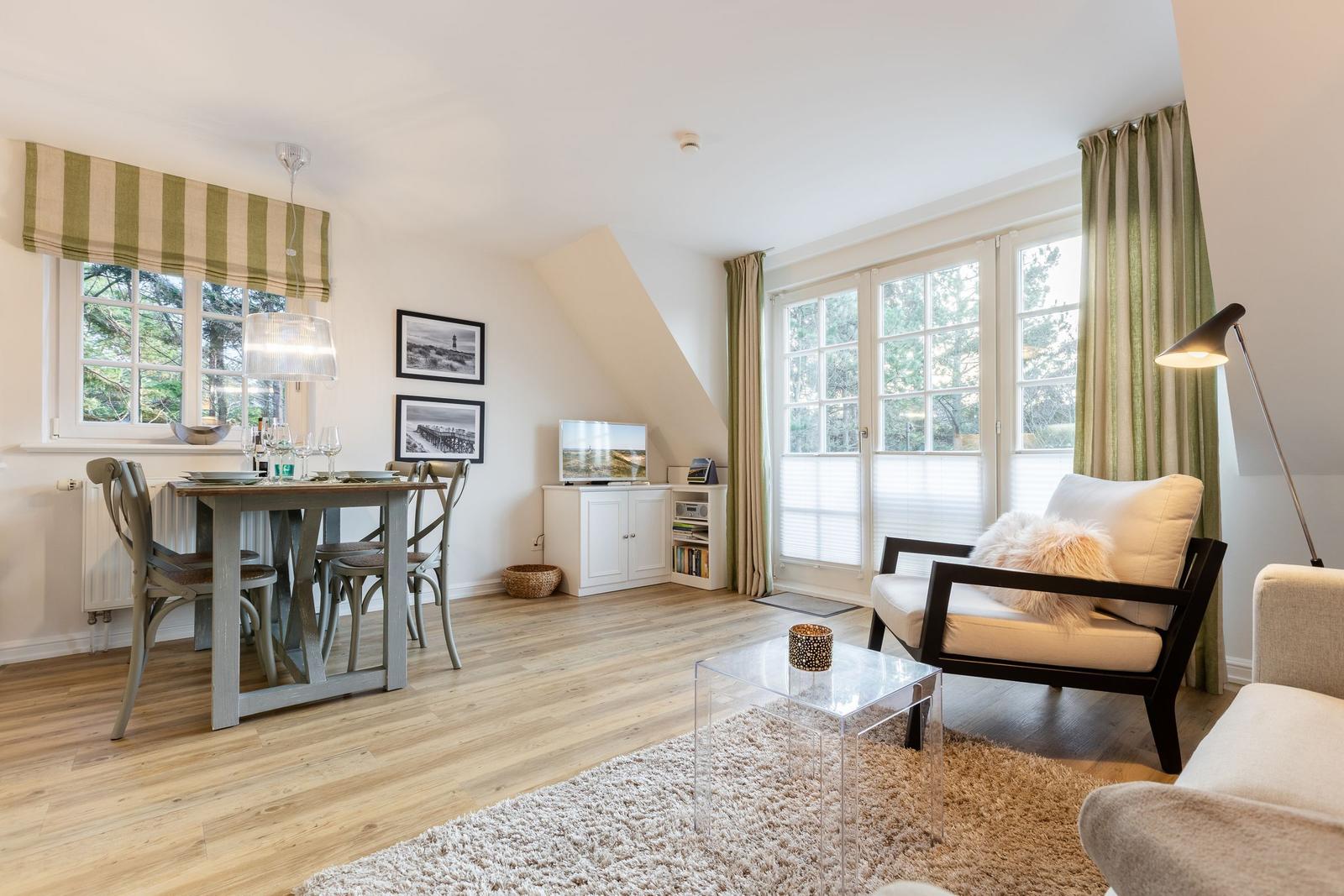 Living and dining area with wooden floor, windows, and furniture.