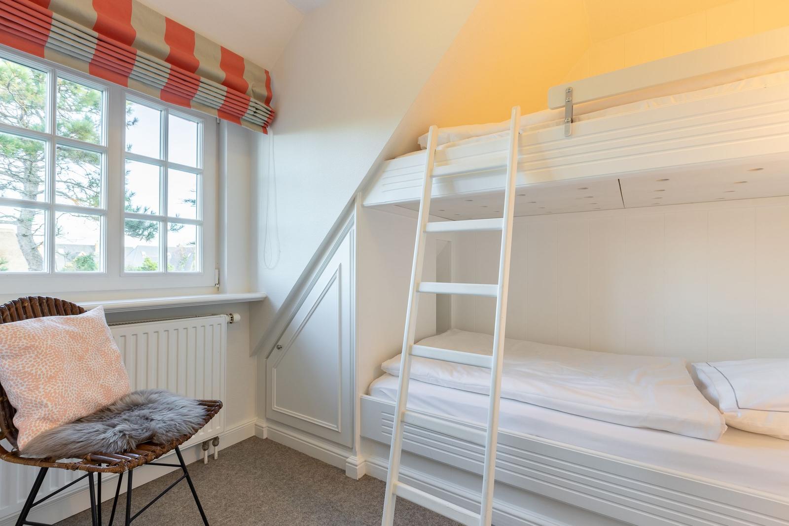 Room with bunk bed, window, and chair with pillow.