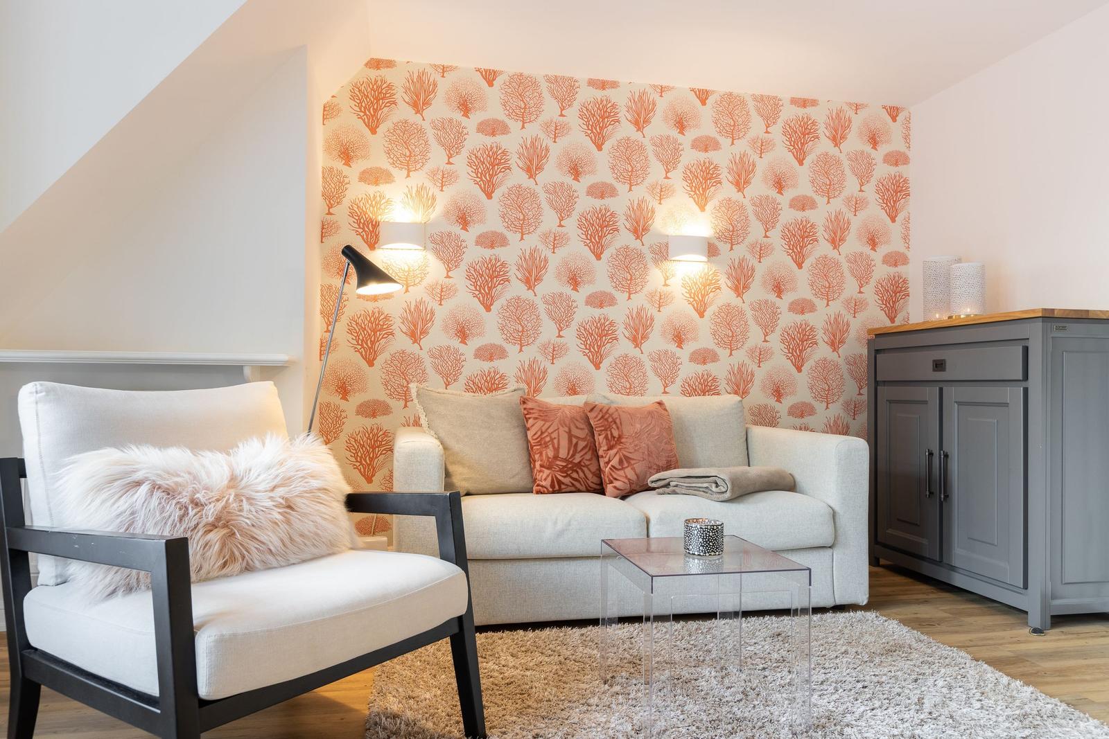 Living room with sofa, armchair, and decorative wallpaper