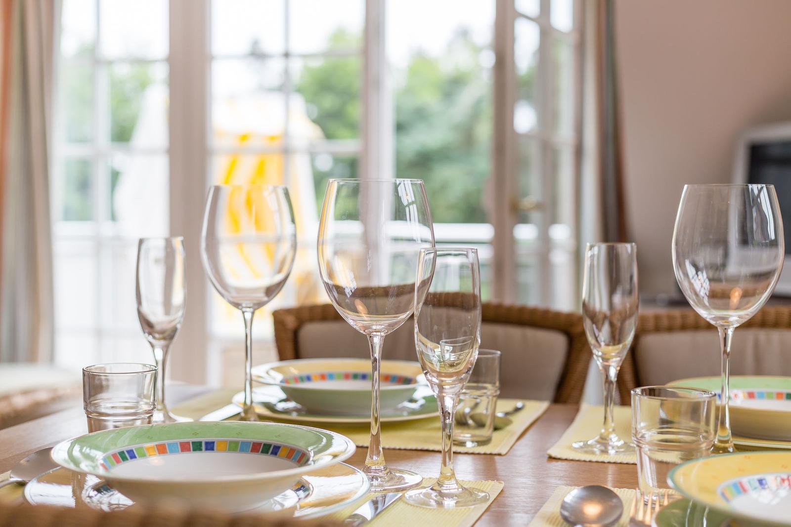Table with plates, glasses, and cutlery on yellow placemats.