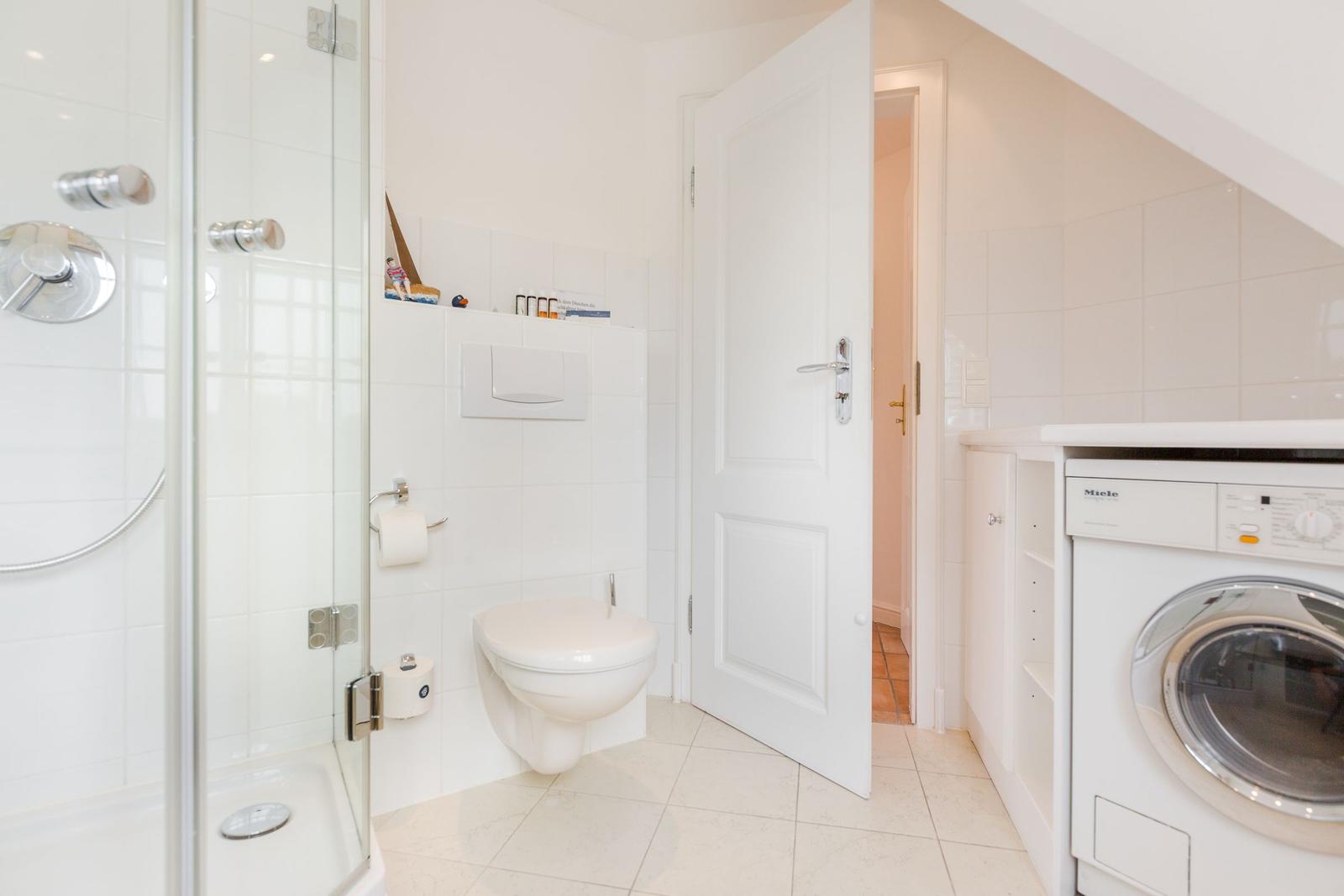 Bathroom with shower, toilet, and washing machine.