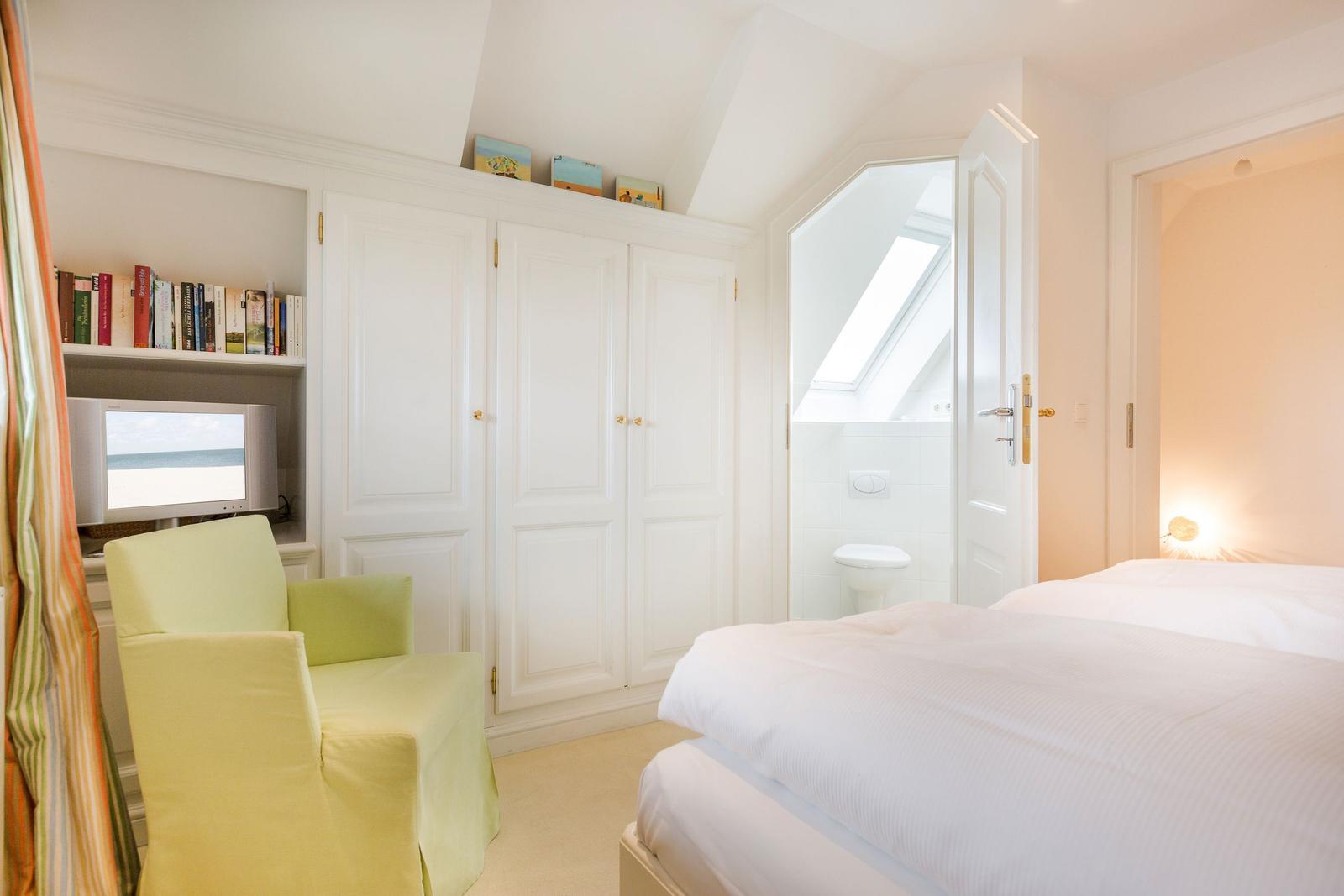 Bedroom with bed, wardrobe, and TV. Door leads to the toilet.