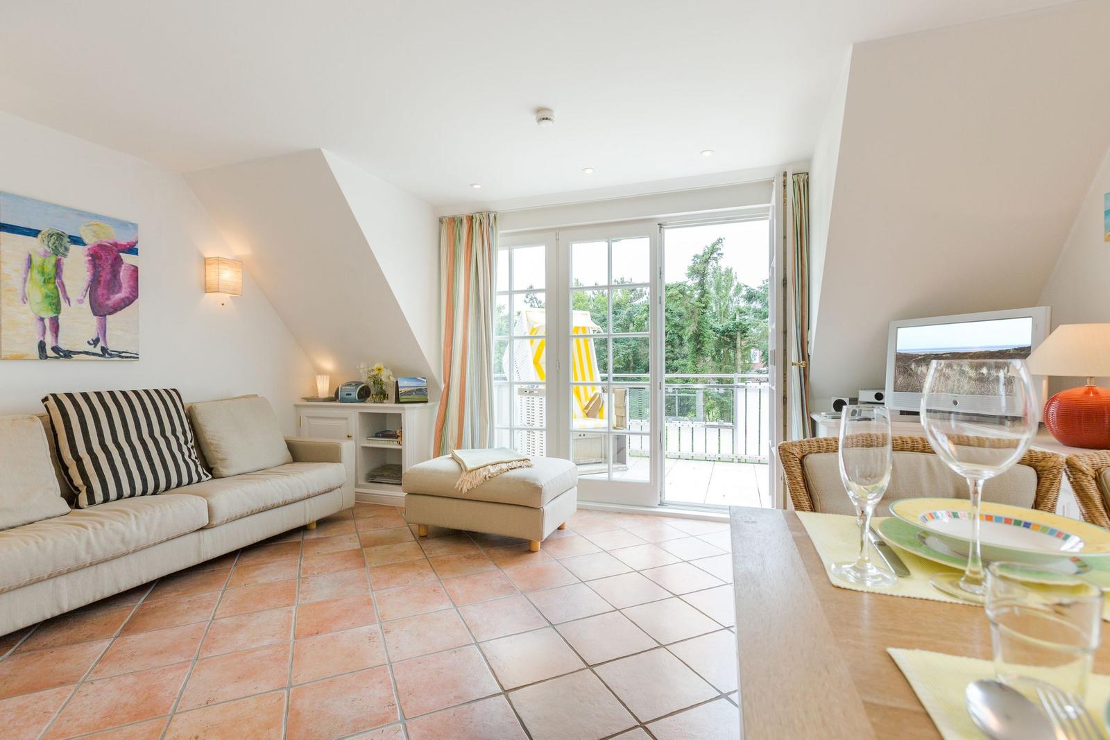 Living and dining area with terrace, sofa, dining table, and TV.