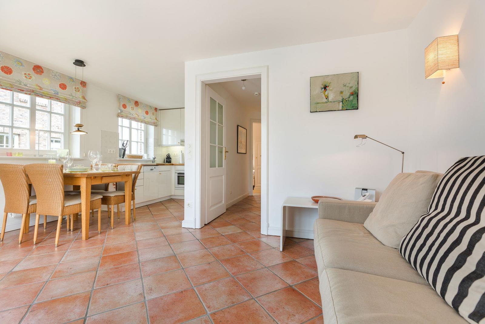 Living and dining area with terracotta floor, sofa, and dining table.