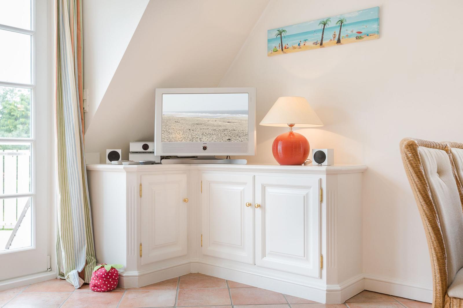 TV on white cabinet, lamp and beach picture on wall