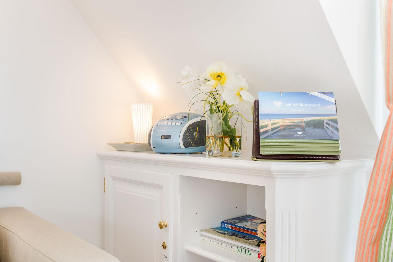 White cabinet with radio, flowers, and brochures in attic room.