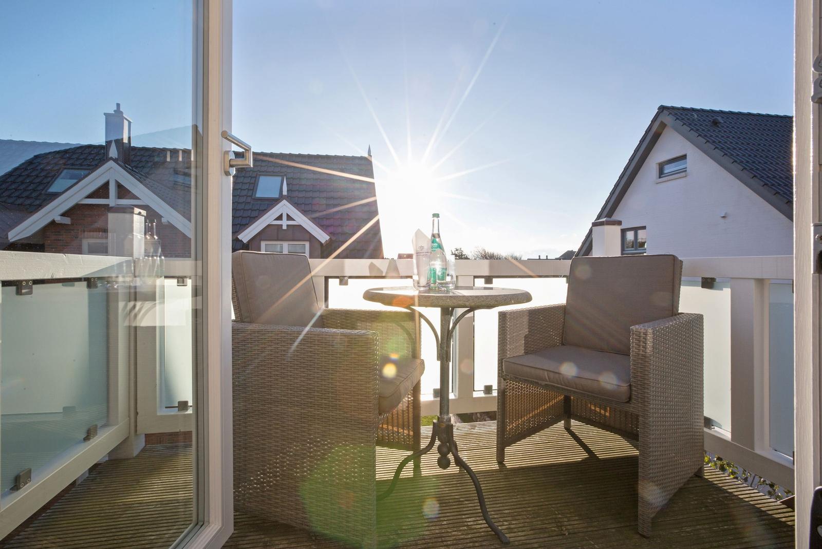 Terrace with two chairs and table. Sun shining. Background: houses.
