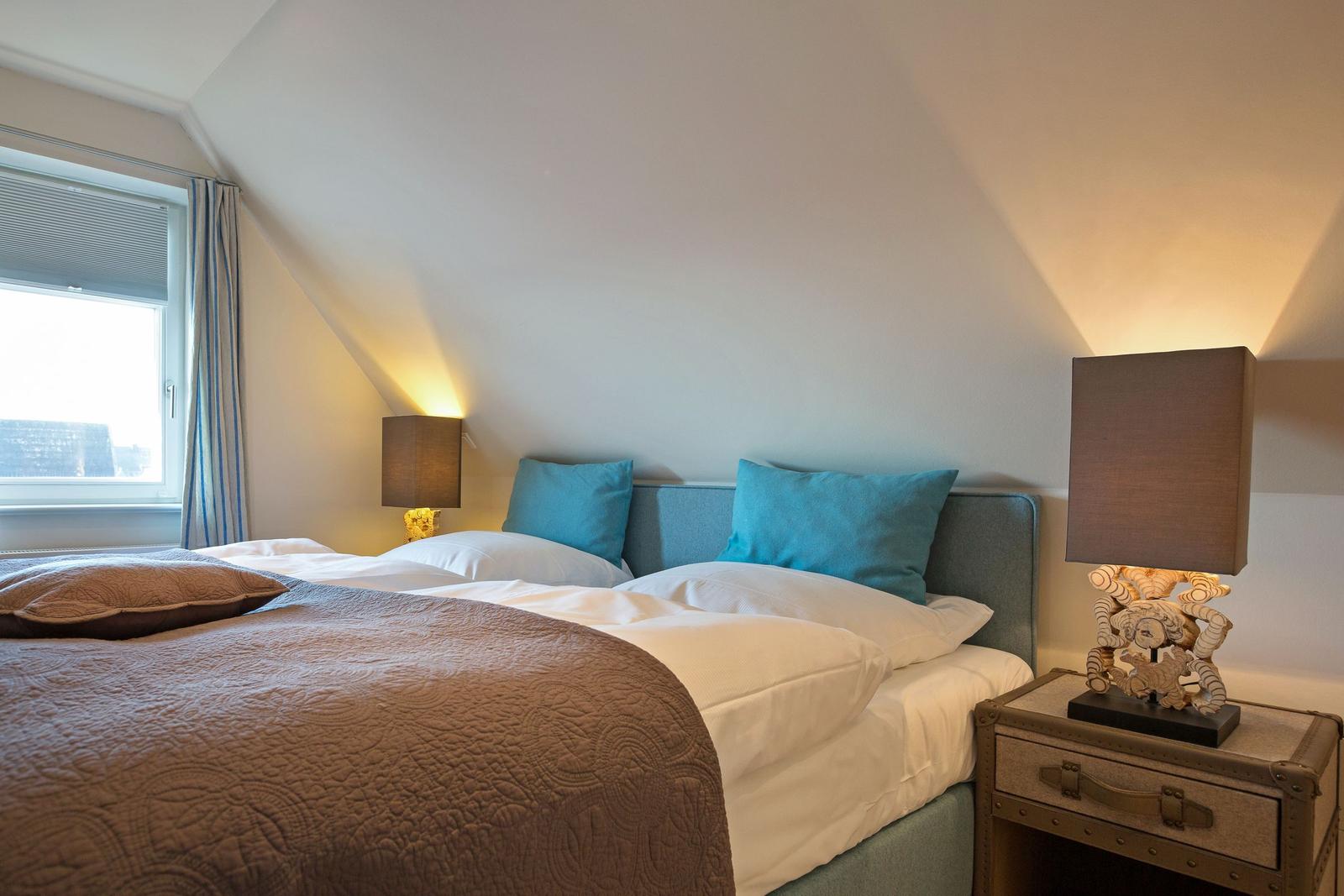 Bedroom with bed, two nightstands, and lamp. Window with curtains.