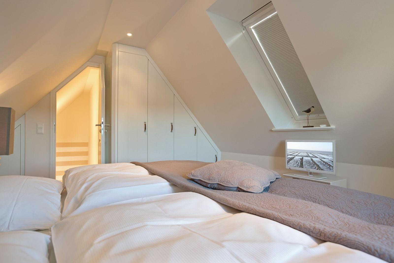 Attic room with bed, wardrobe, and skylight.