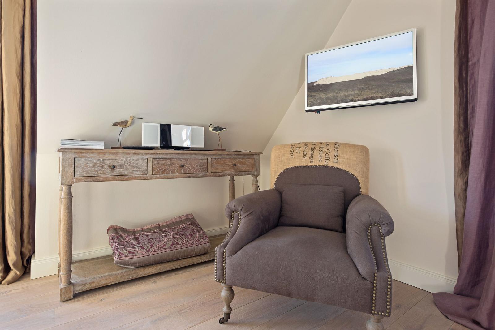 A room with a chair, a desk, and a wall-mounted TV unit.