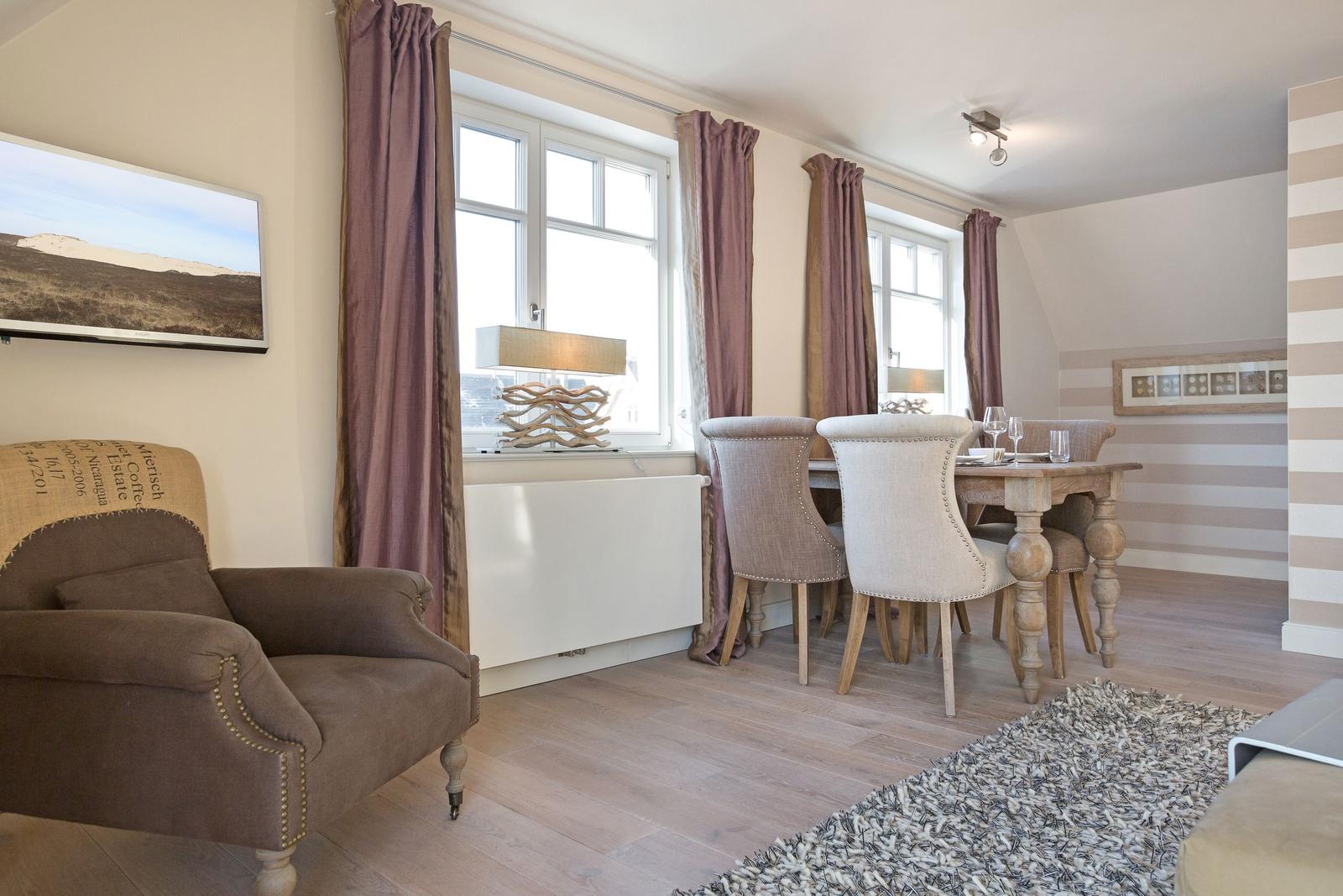 Dining room with table, chairs, and windows with curtains.