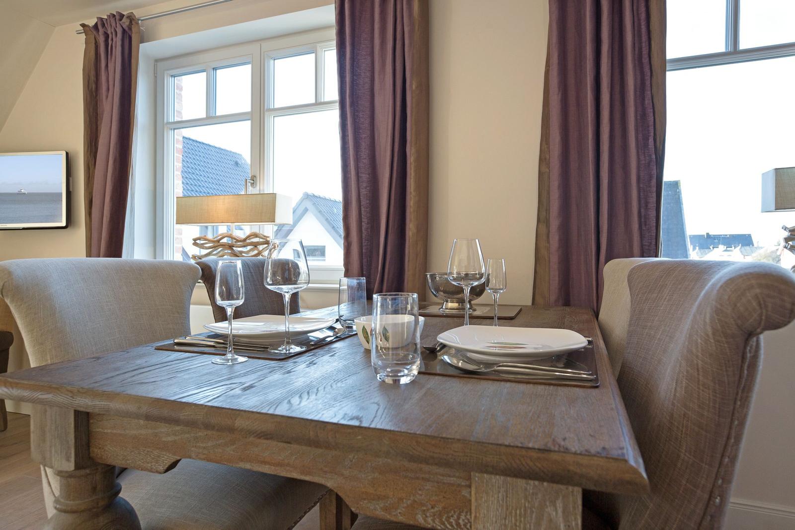 Dining table with chairs, table setting, and windows with curtains.