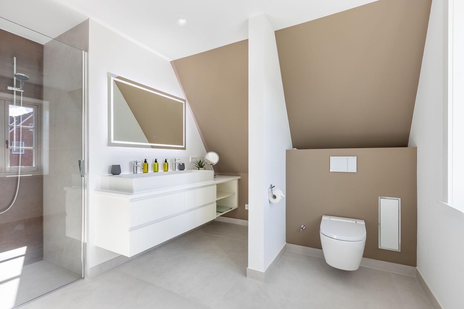 Moderne Dusche, Waschbecken und Toilette in einem geräumigen Badezimmer mit schrägen Wänden.