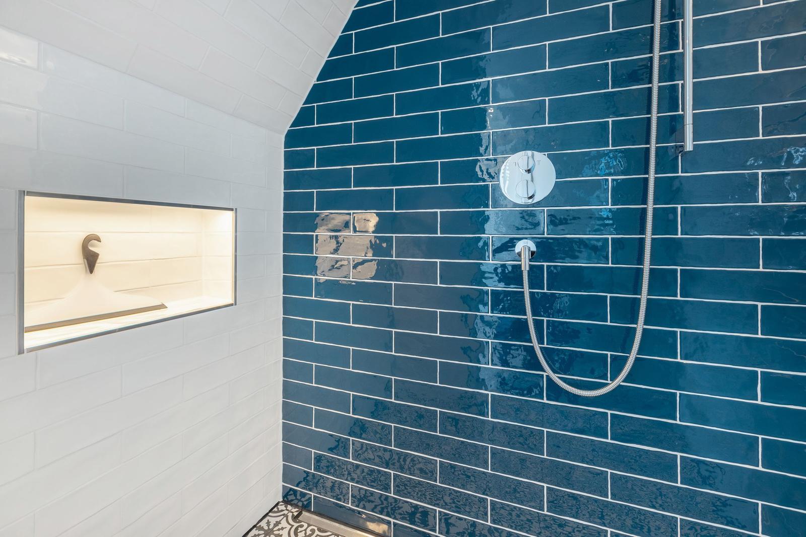 Dusche mit blauen Fliesen und eingebauter Ablage