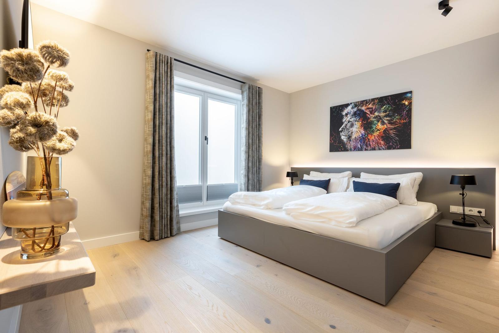 Schlafzimmer mit Bett, Fenster und Wandbild.