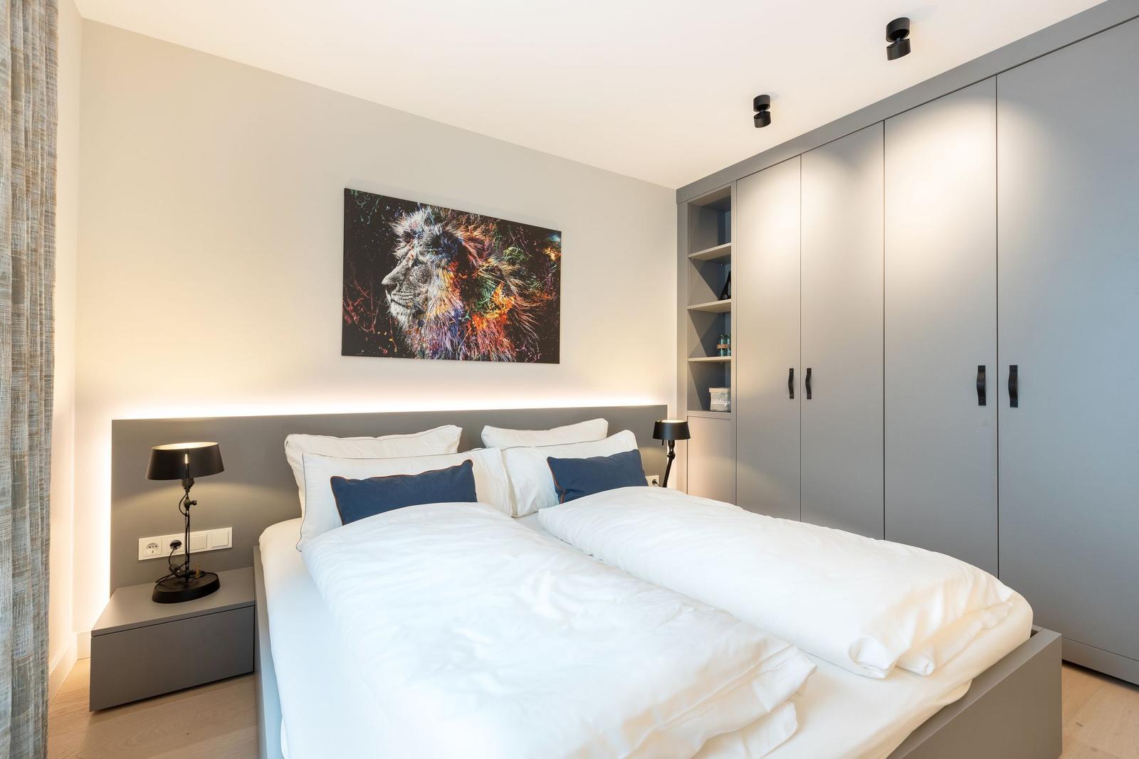 Schlafzimmer mit Doppelbett, Kleiderschrank und Wandbild eines Löwen.