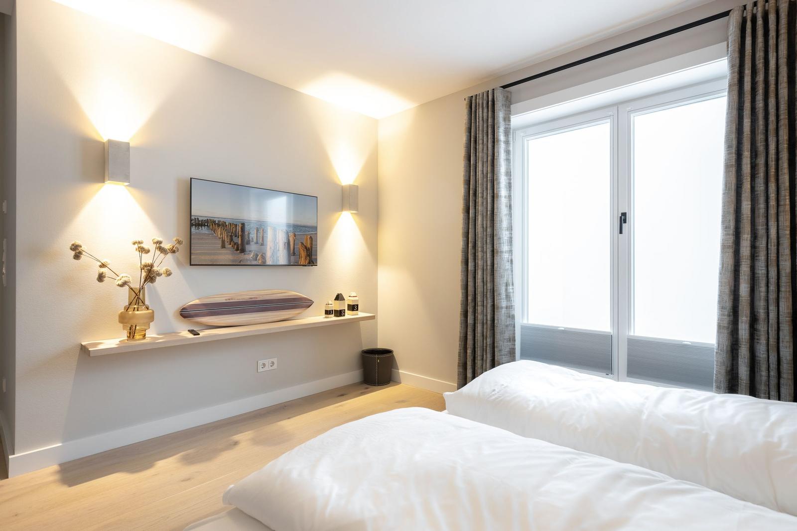 Schlafzimmer mit Doppelbett, Fenster und Wandbild.