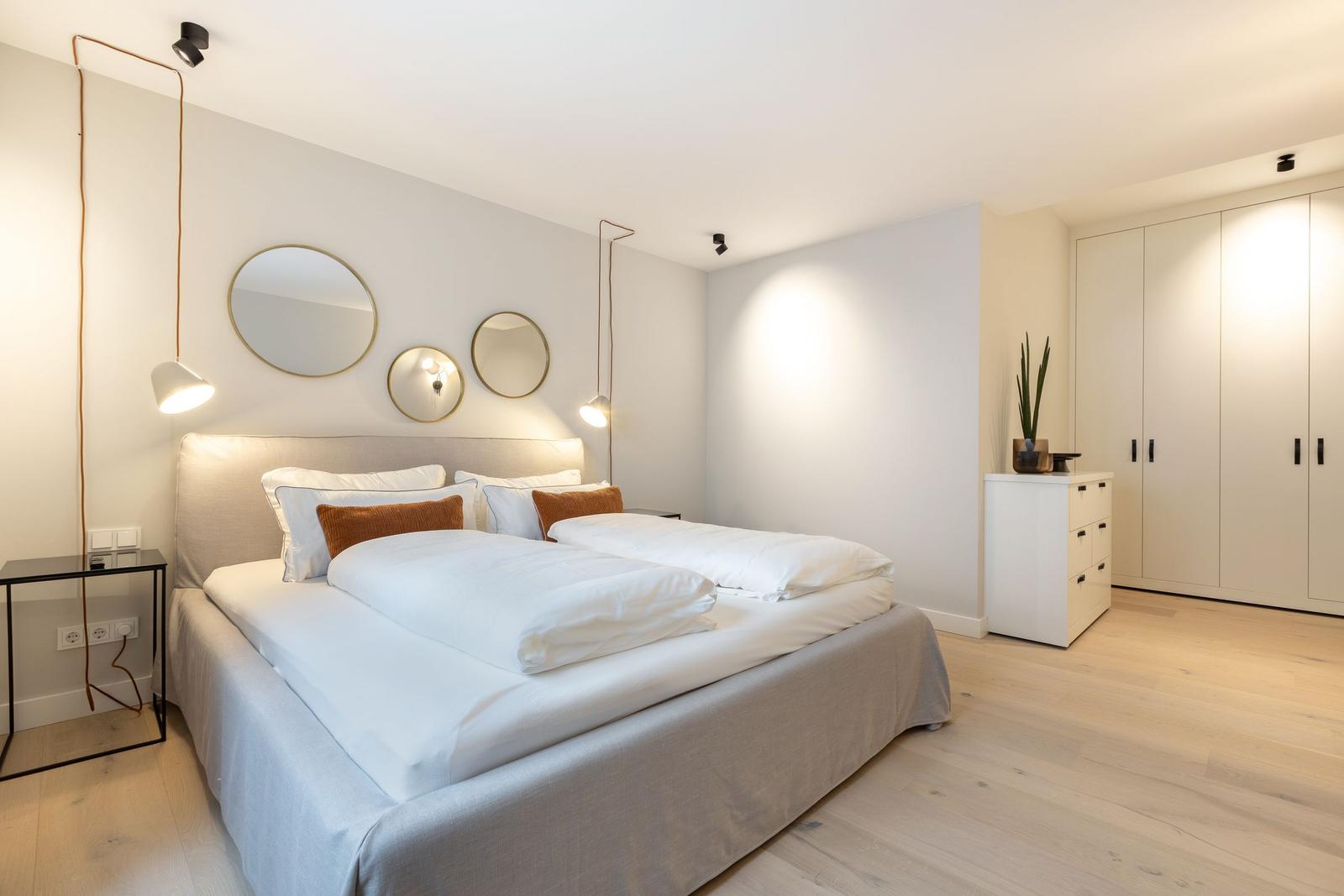 Schlafzimmer mit Doppelbett, drei runden Spiegeln und Kleiderschrank.
