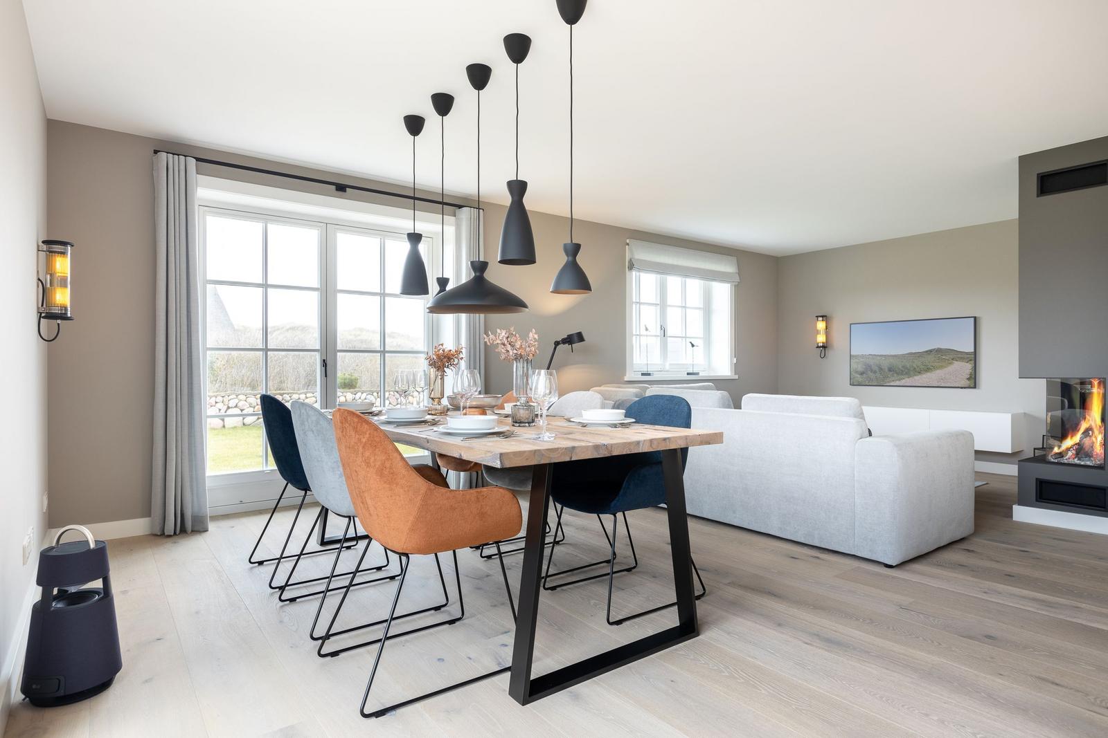 Esszimmer mit Tisch, Stühlen und Fenster. Wohnbereich mit Sofa und Kamin.