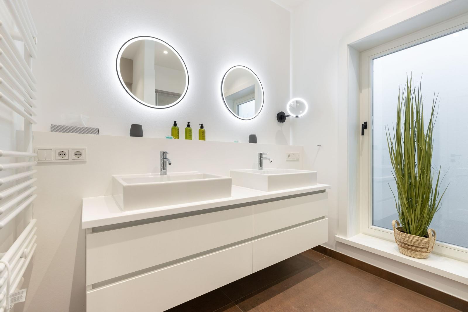 Zwei Waschbecken mit Spiegeln und Pflanze am Fenster