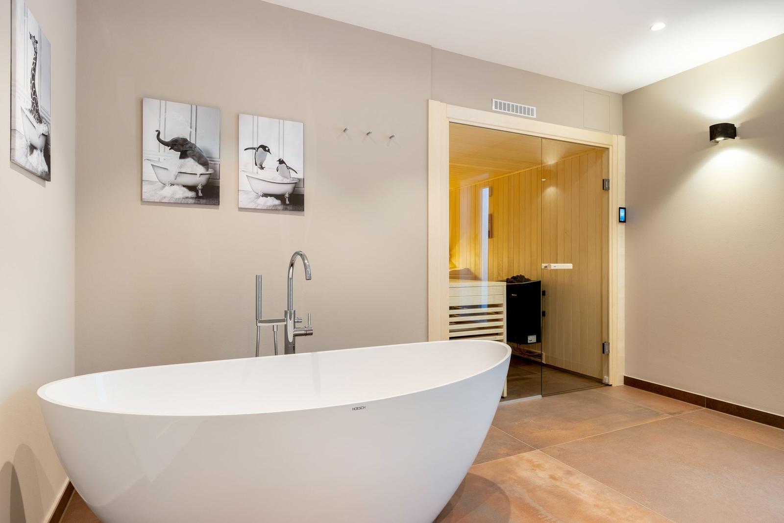 Bad mit freistehender Badewanne und Blick in die Sauna.