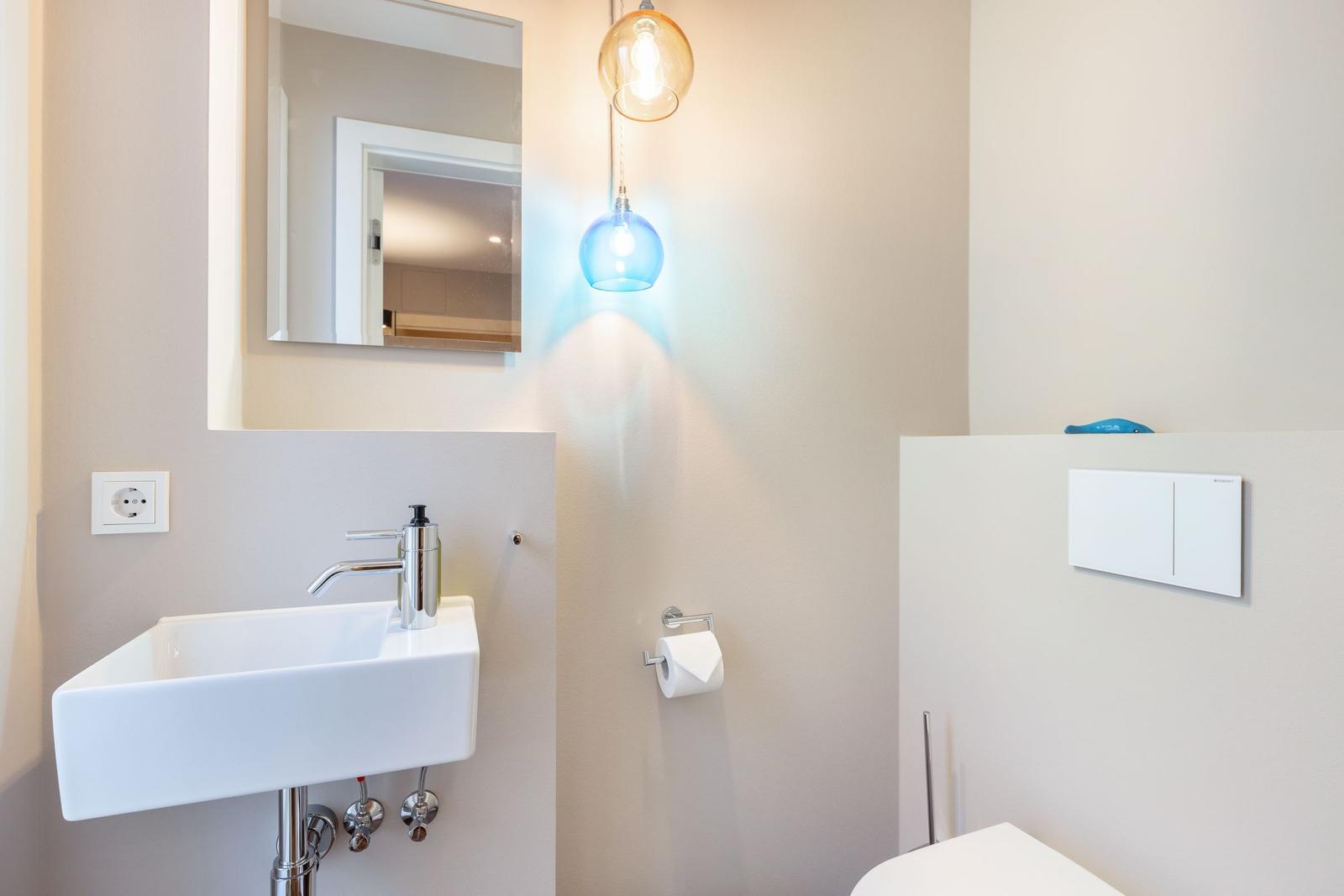 Badezimmer mit Waschbecken, Spiegel und Toilette