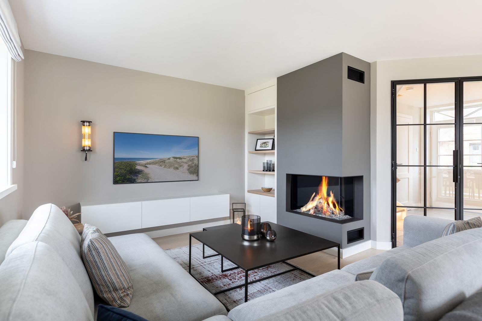 Wohnzimmer mit Kamin, Sofa und Fernseher an der Wand.