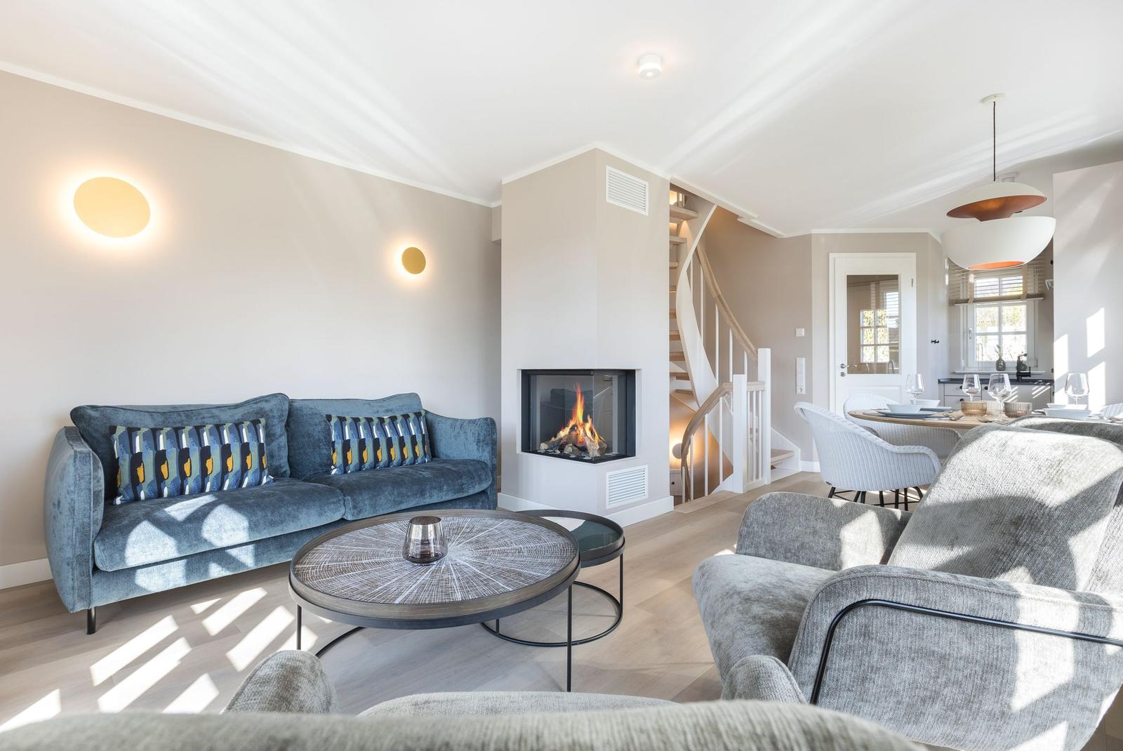 Living room with sofa, fireplace, and dining area in background.
