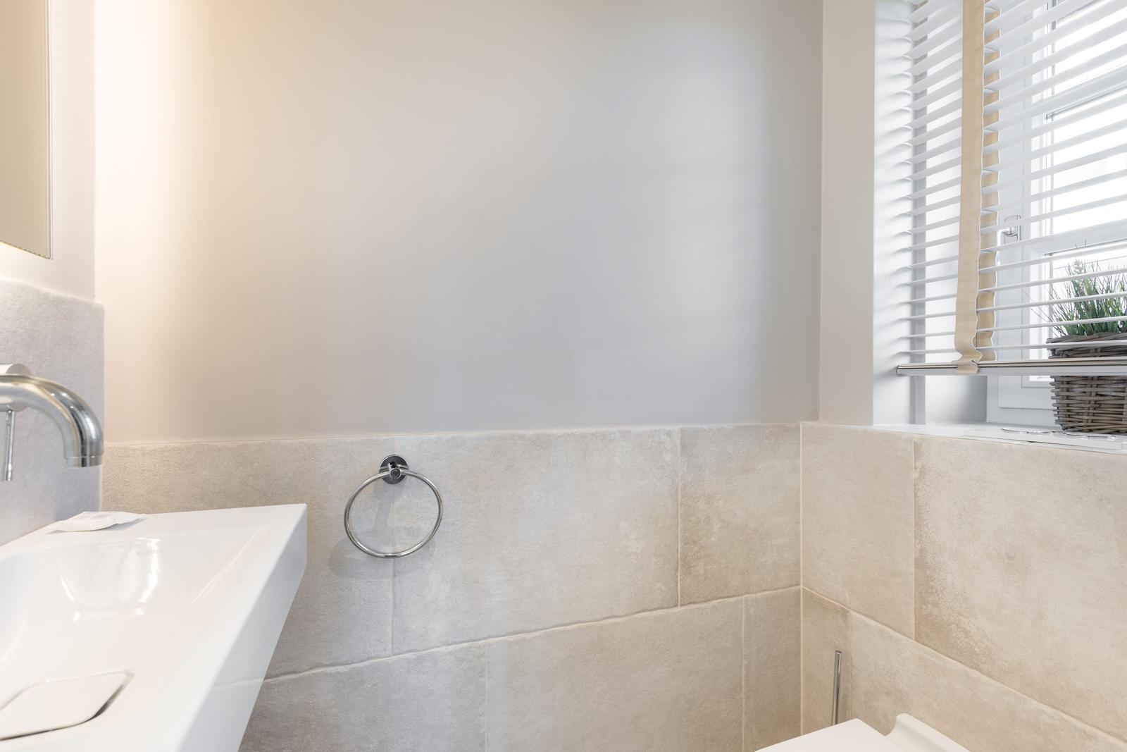 Bathroom with sink, towel ring, and window with blinds.