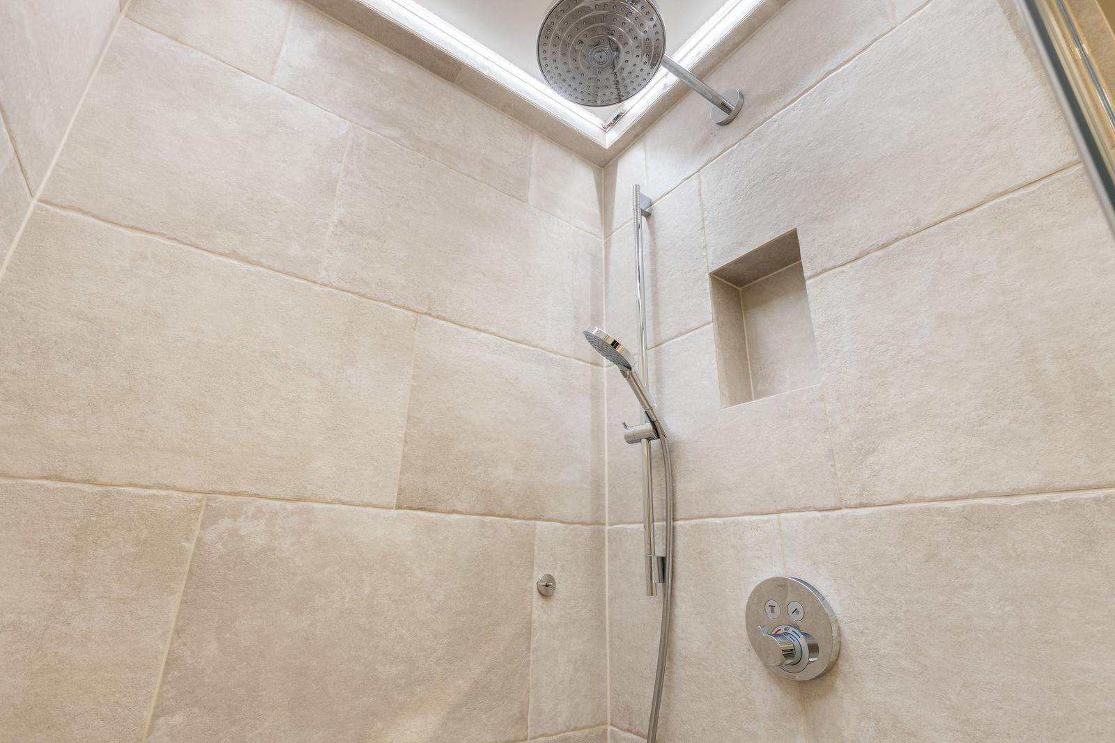 Shower cabin with shower head, handheld shower, and built-in shelf
