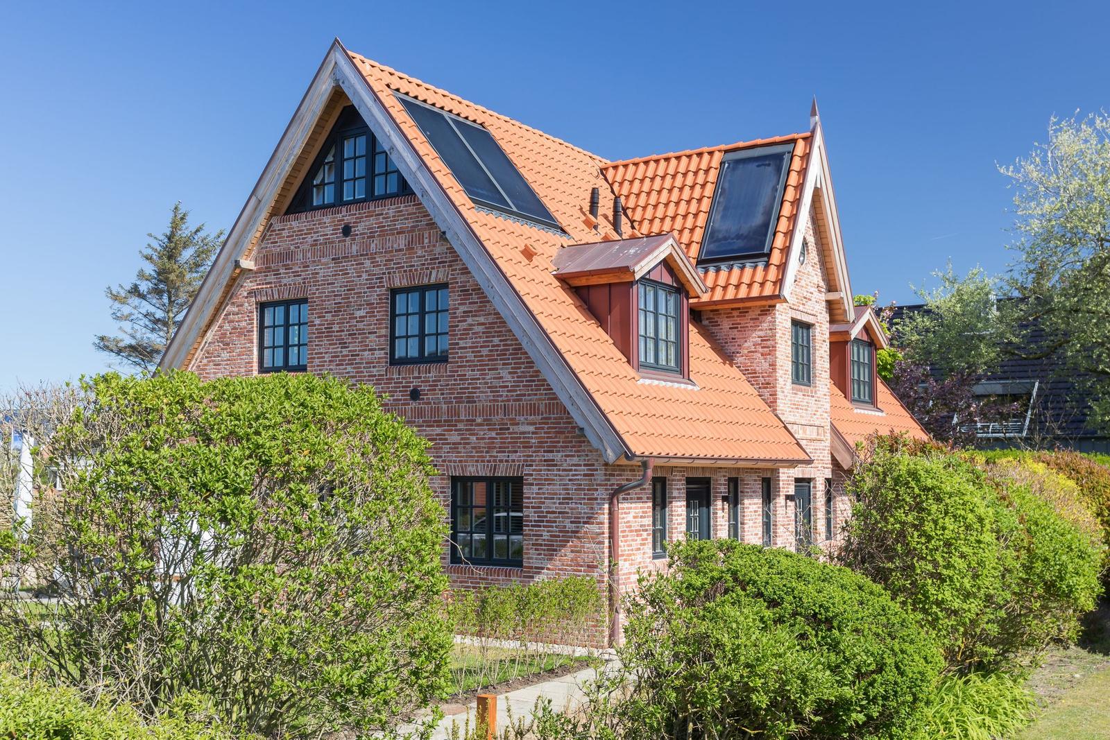 Two-story brick house with red tiled roof and solar panels.