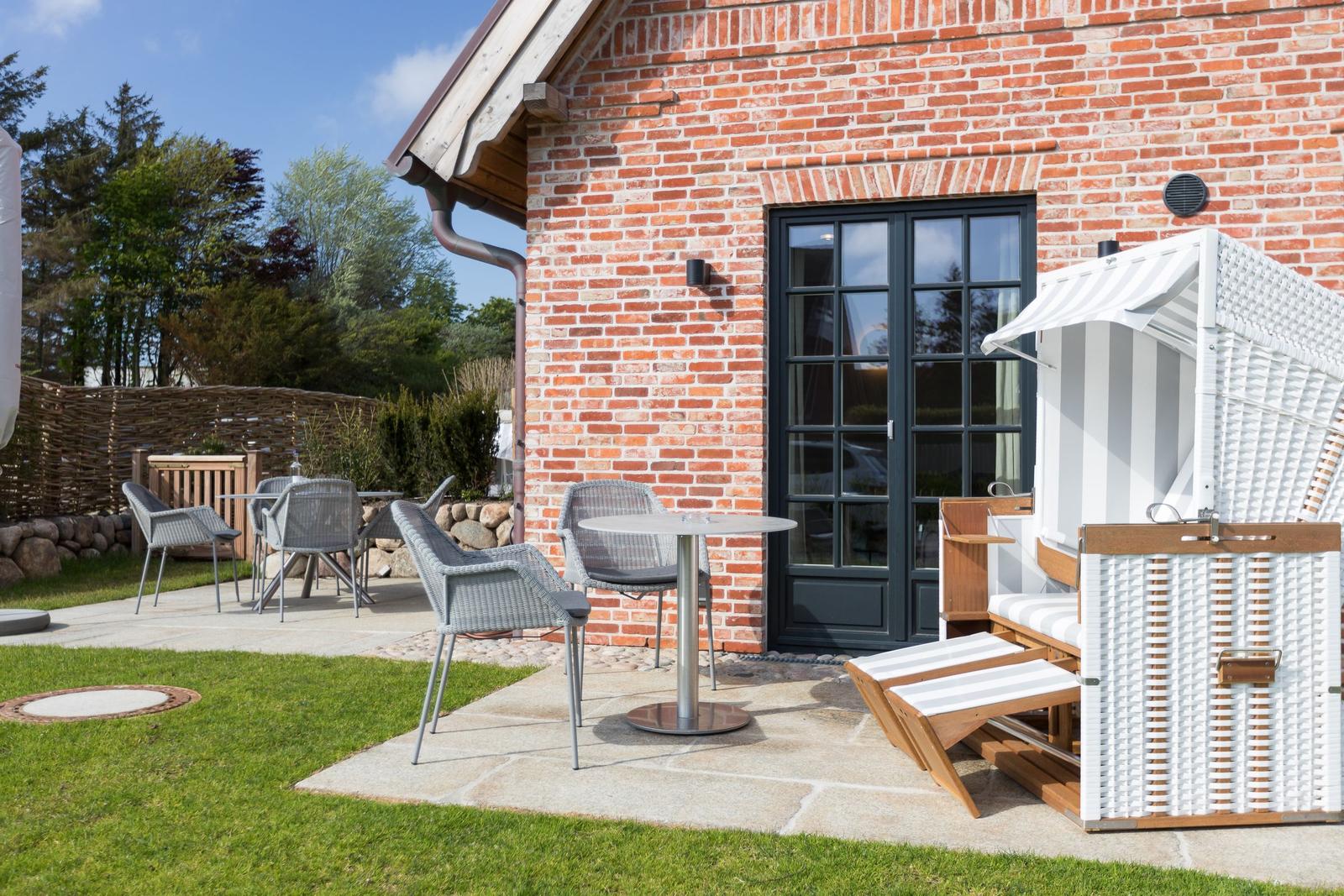 Red brick building with terrace, table, chairs, and beach chair.