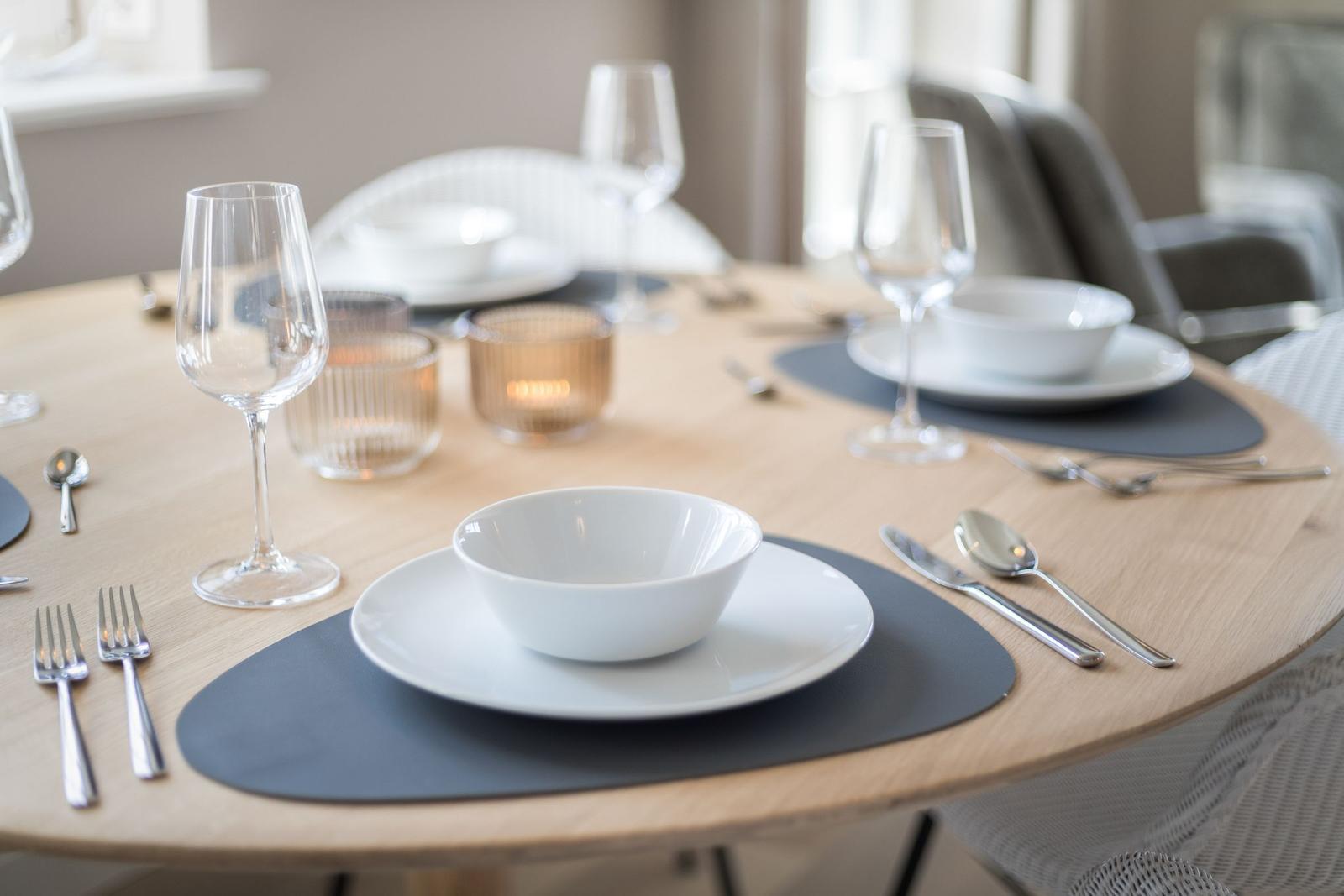 Round table set with dinnerware and glasses for four people.