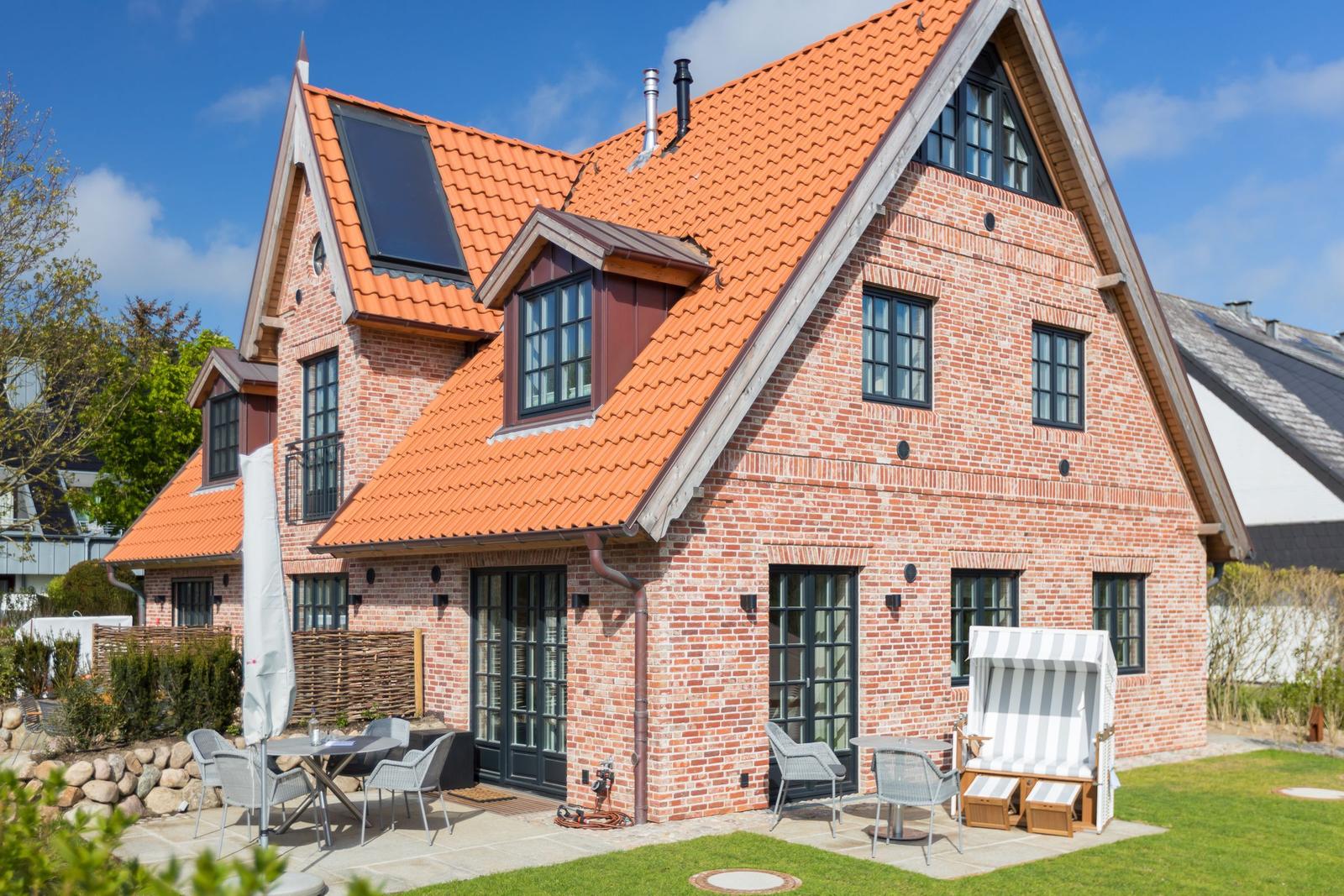 Red tile roof, brick house with patio and garden furniture.