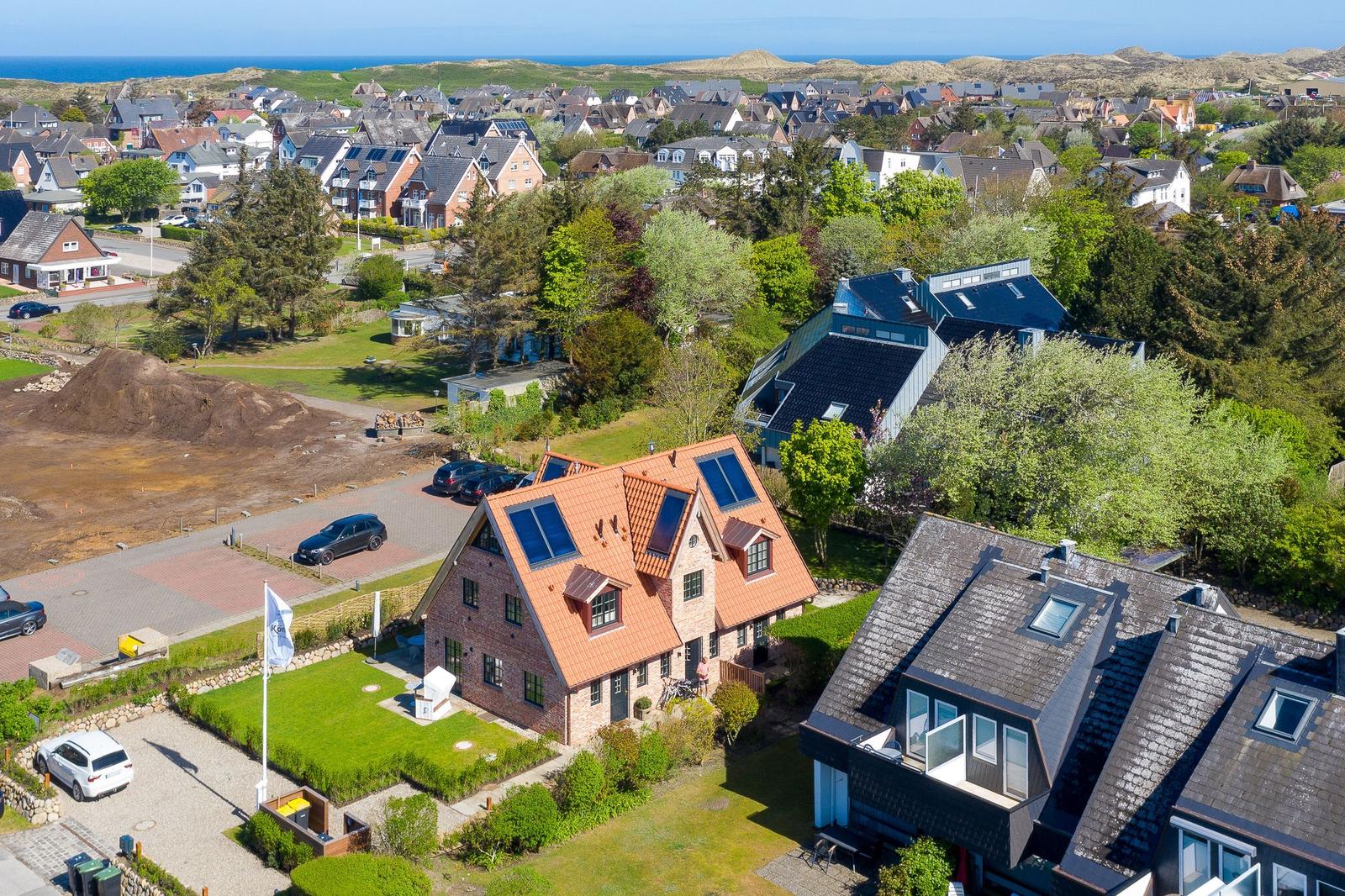 House with red roof and solar panels in green surroundings